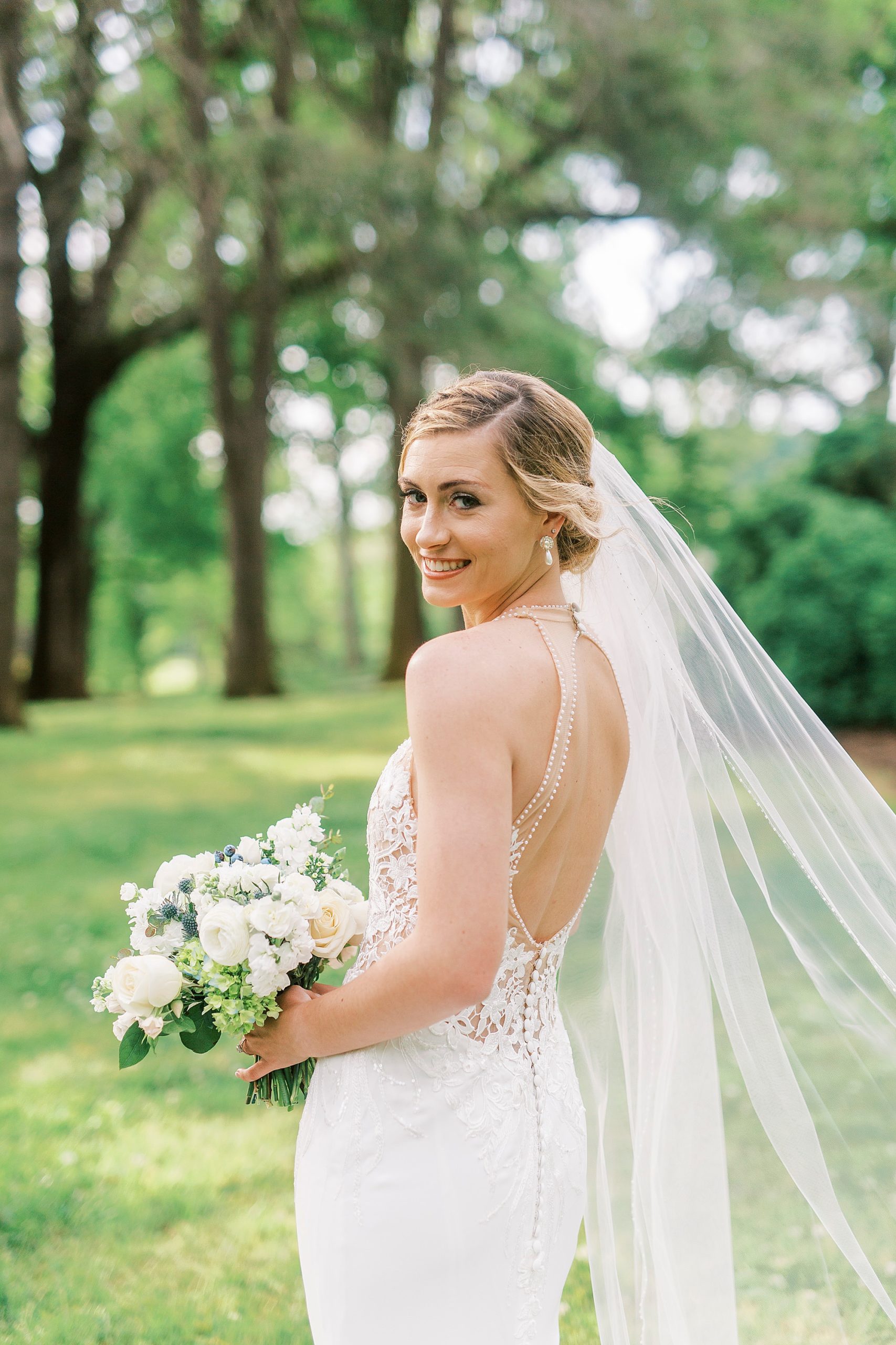 bride holds bouquet with veil behind her during Tanglewood bridal portraits