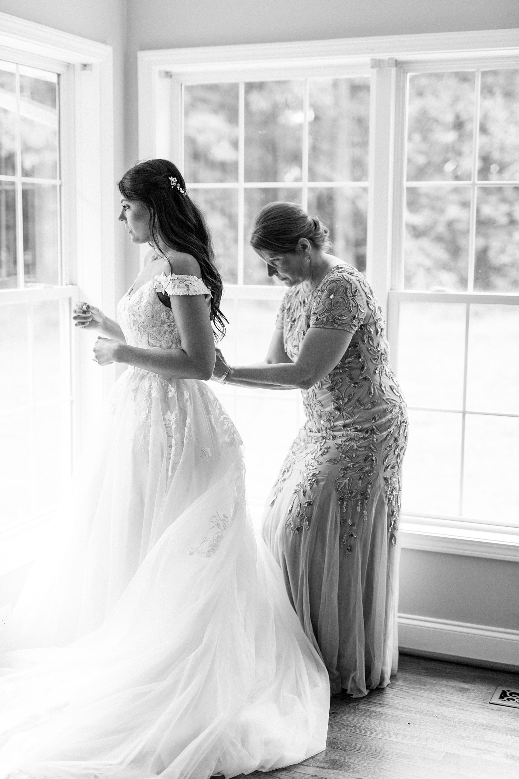 mom helps daughter with wedding gown