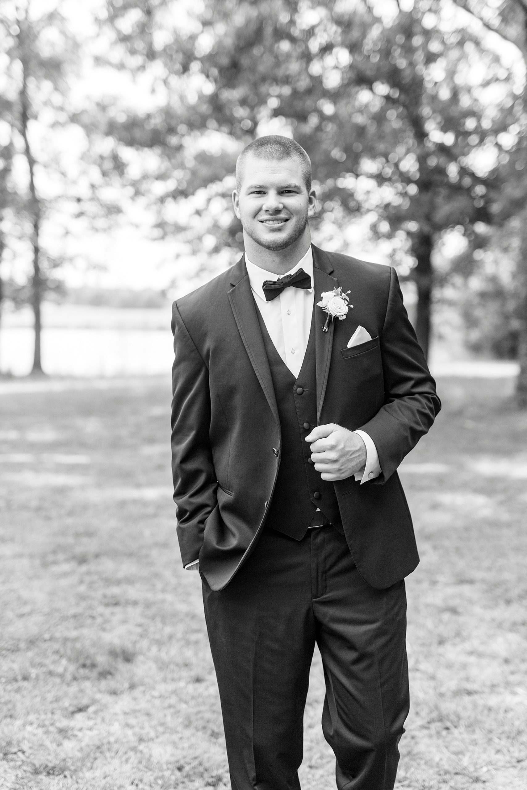 groom poses holding lapel on suit