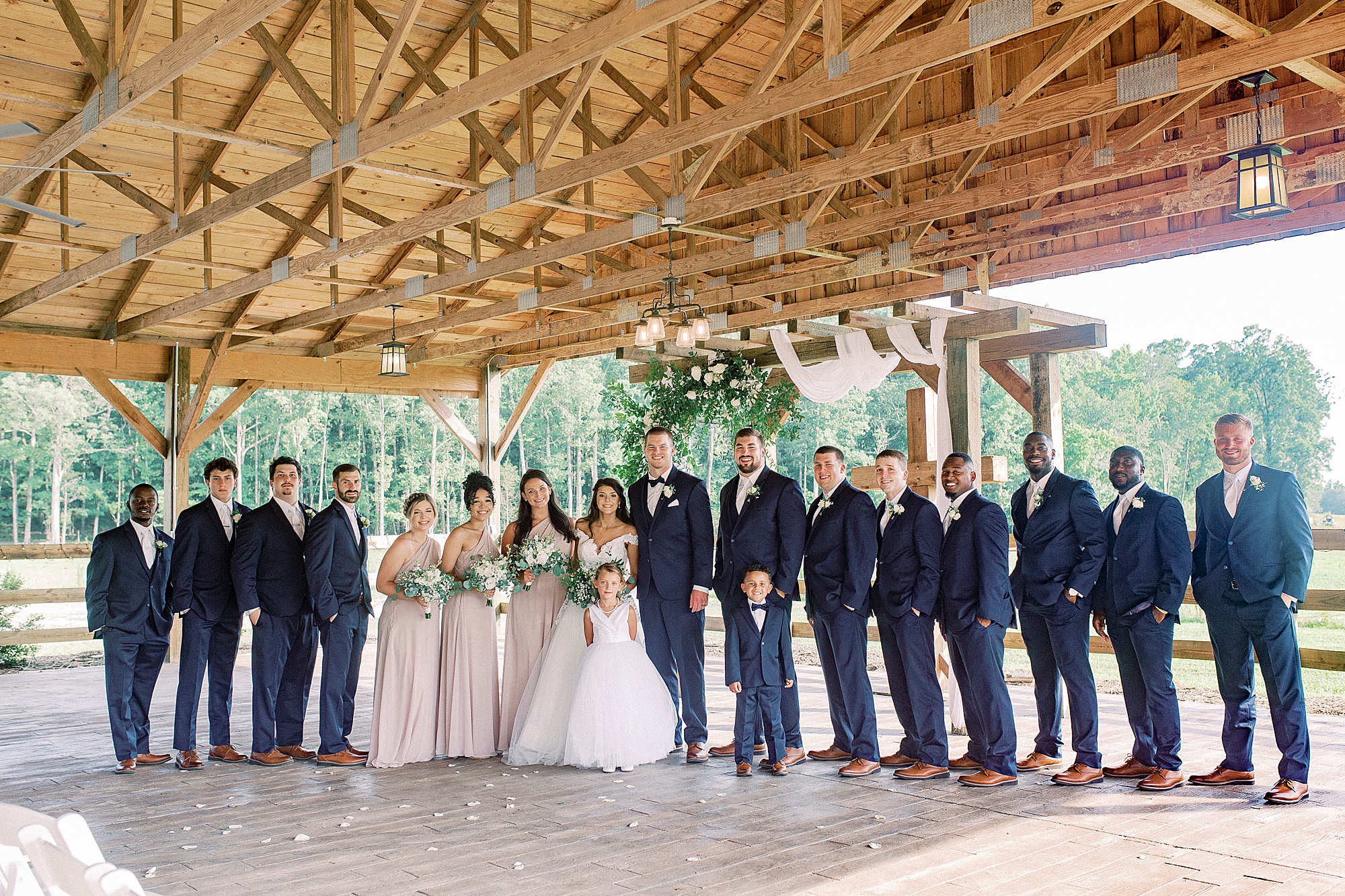 bride and groom pose with wedding party at The Farmstead