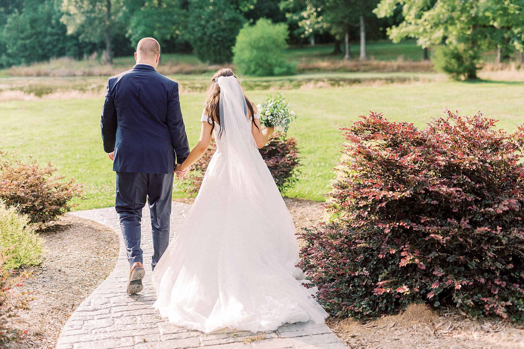 bride and groom walk through garden at The Farmstead