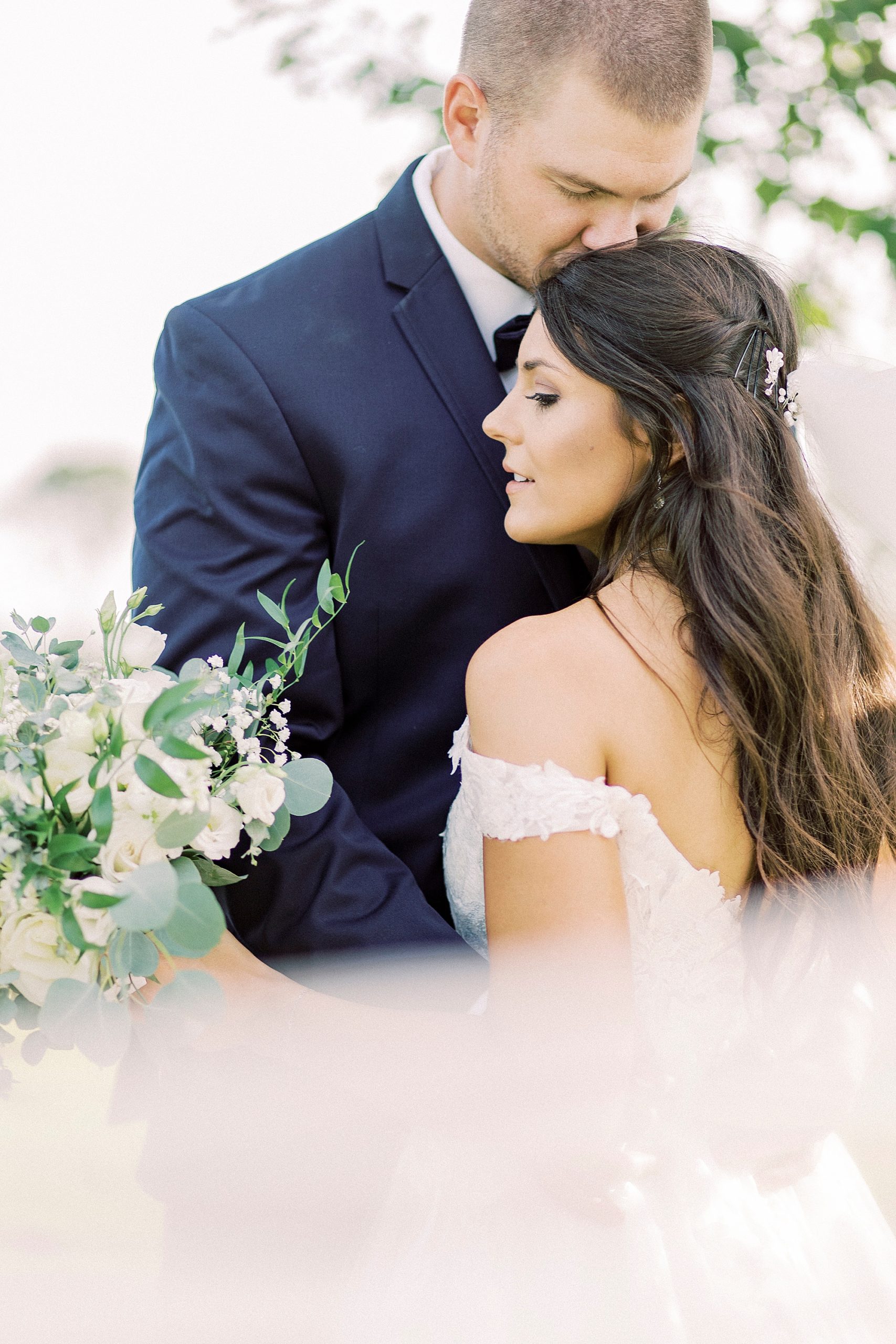 groom kisses bride's forehead during wedding photos