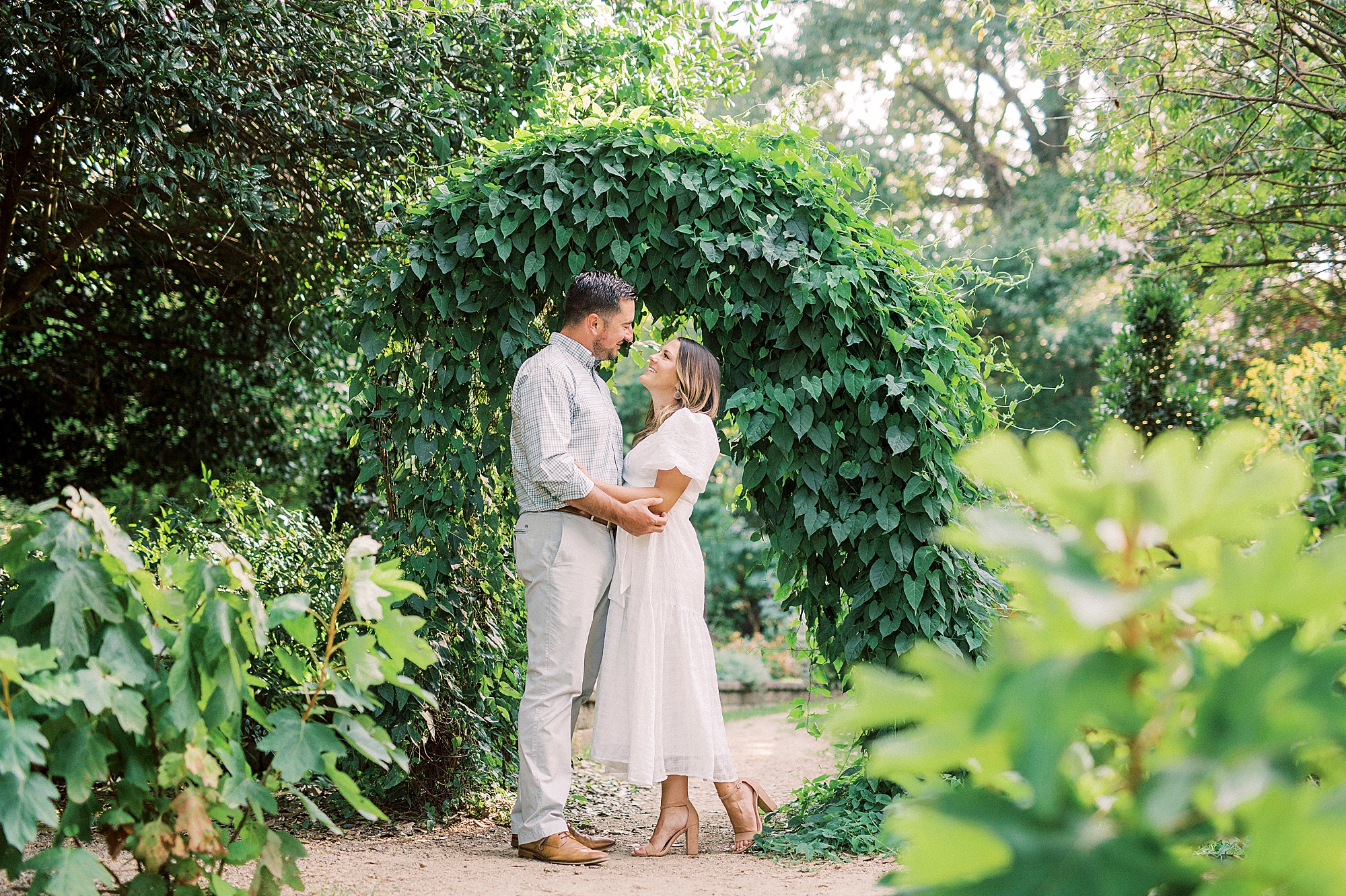 bride and groom pose under ivy covered arch in McGill Rose Garden