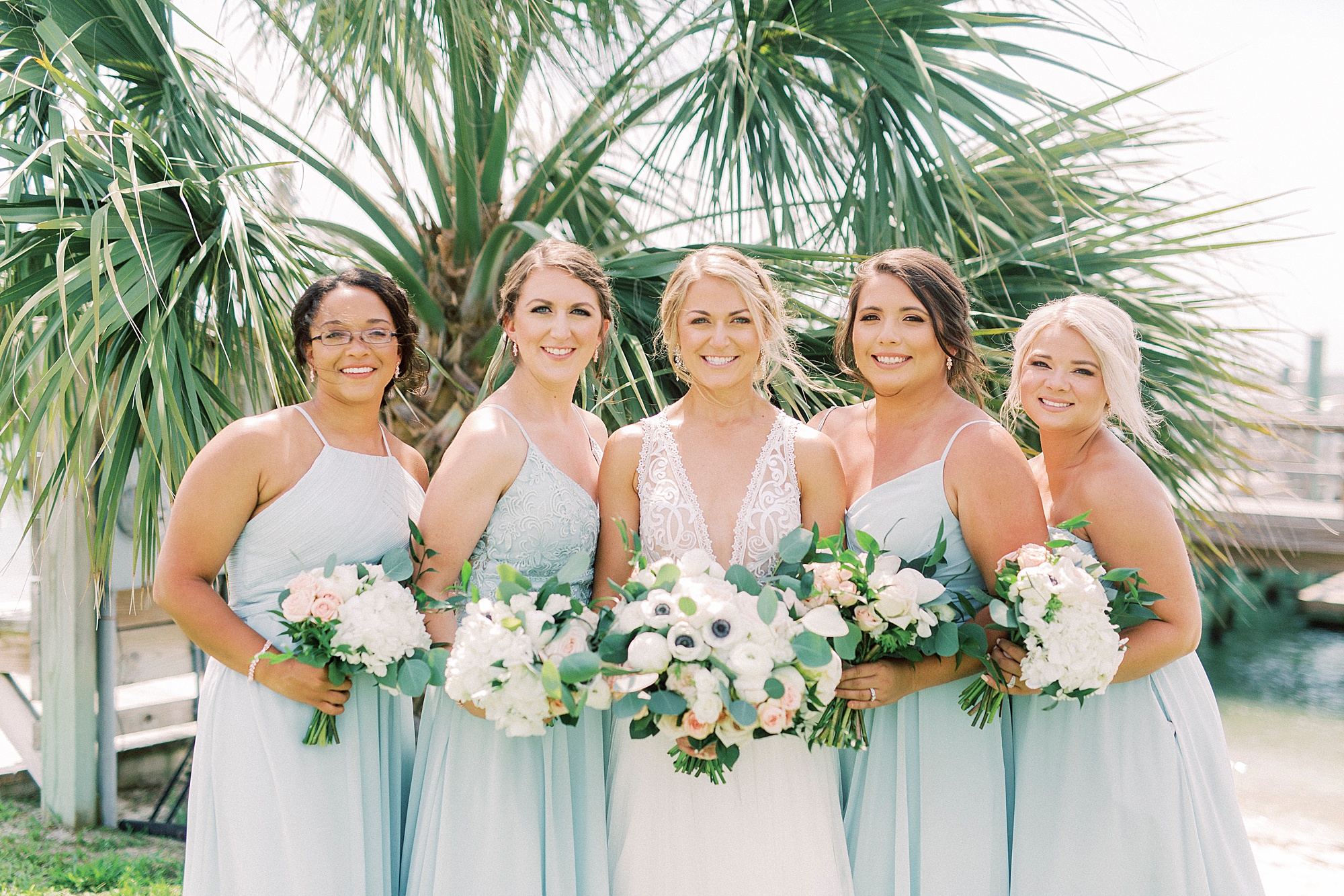 bride smiles with bridesmaids in light blue dresses