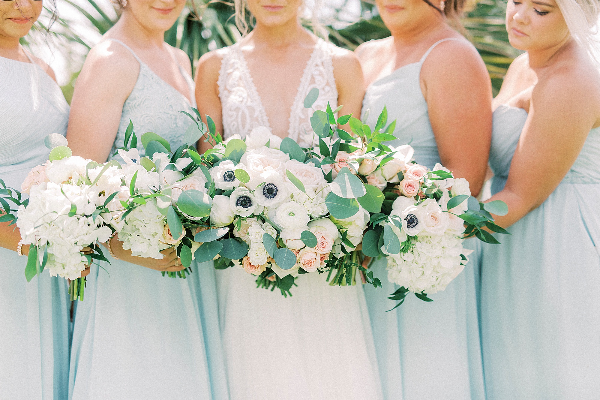 bridesmaids hold bouquets of pink and white flowers for beach wedding