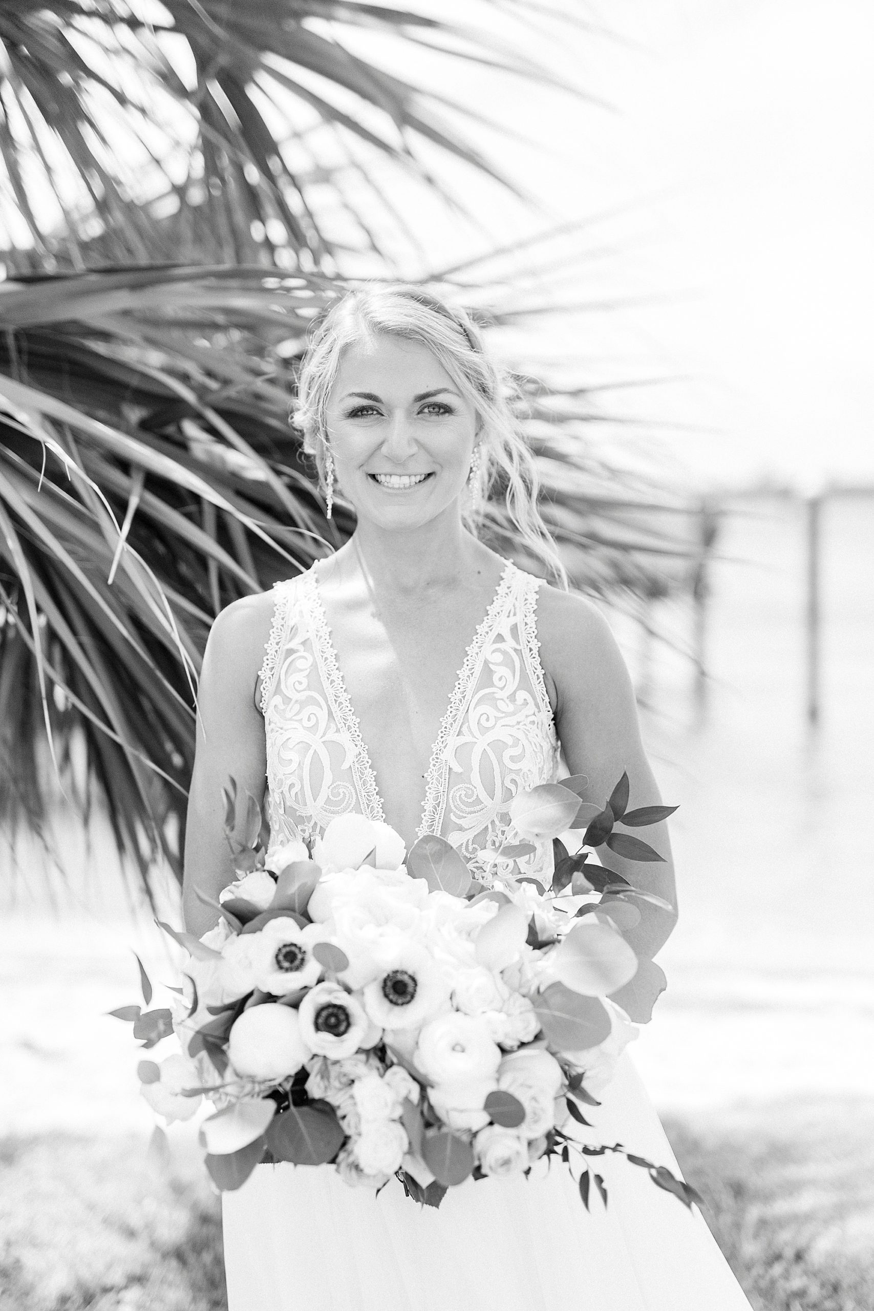 bride holds bouquet by palm tree before Oceanic Restaurant wedding