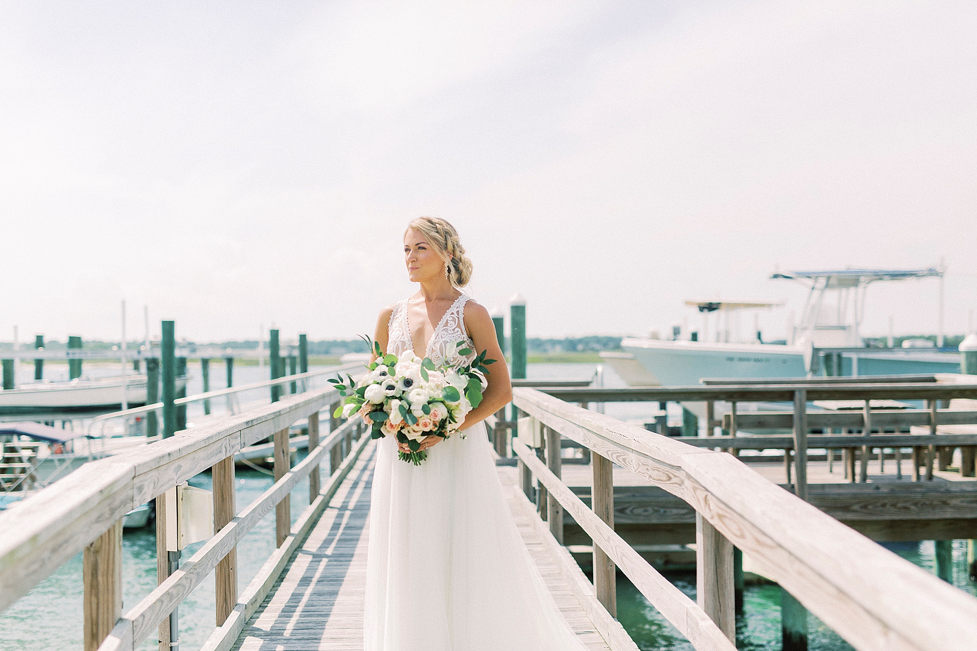 bride stands on pier during portraits at Wrightsville beach