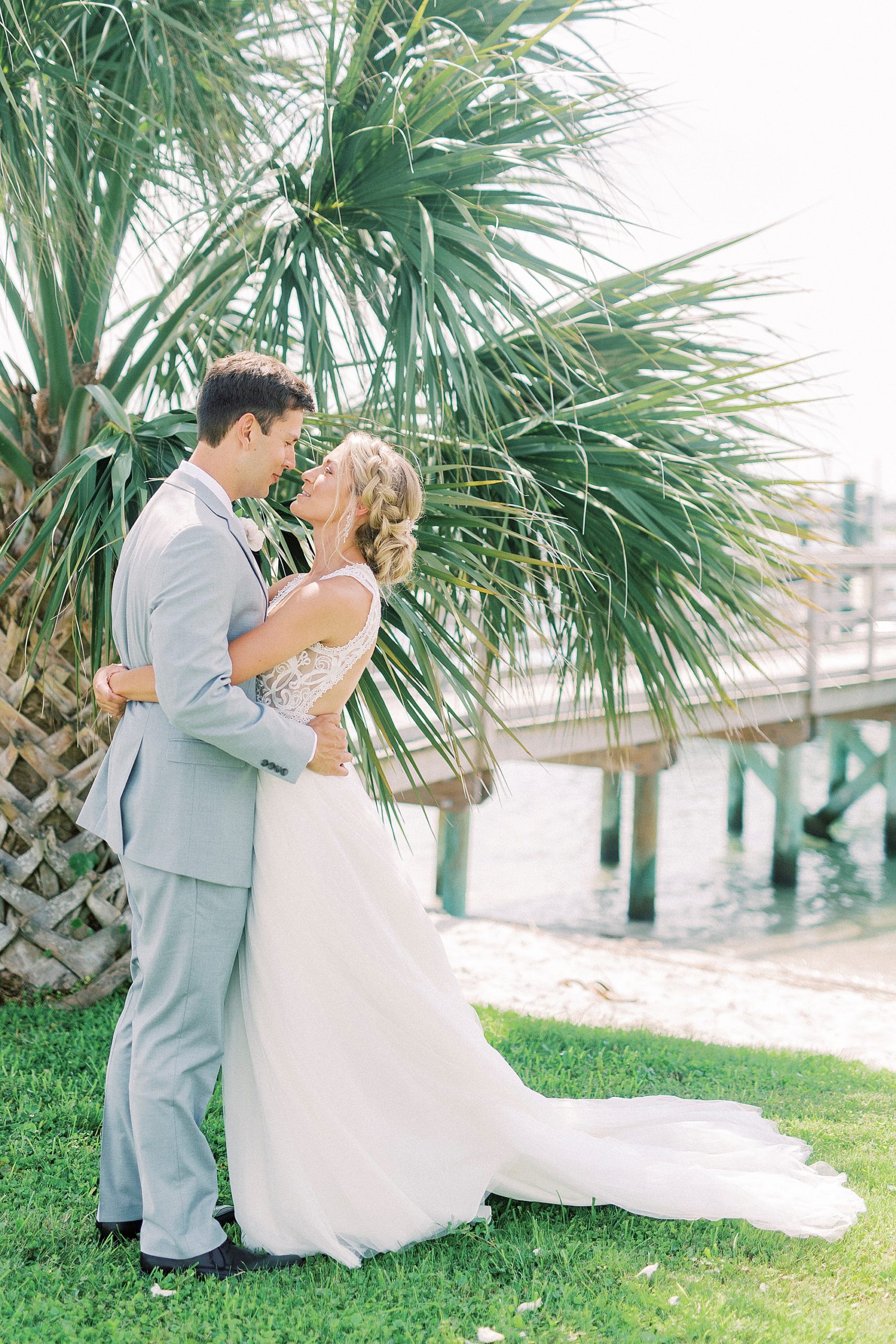 newlyweds hug by palm trees at Wrightsville beach