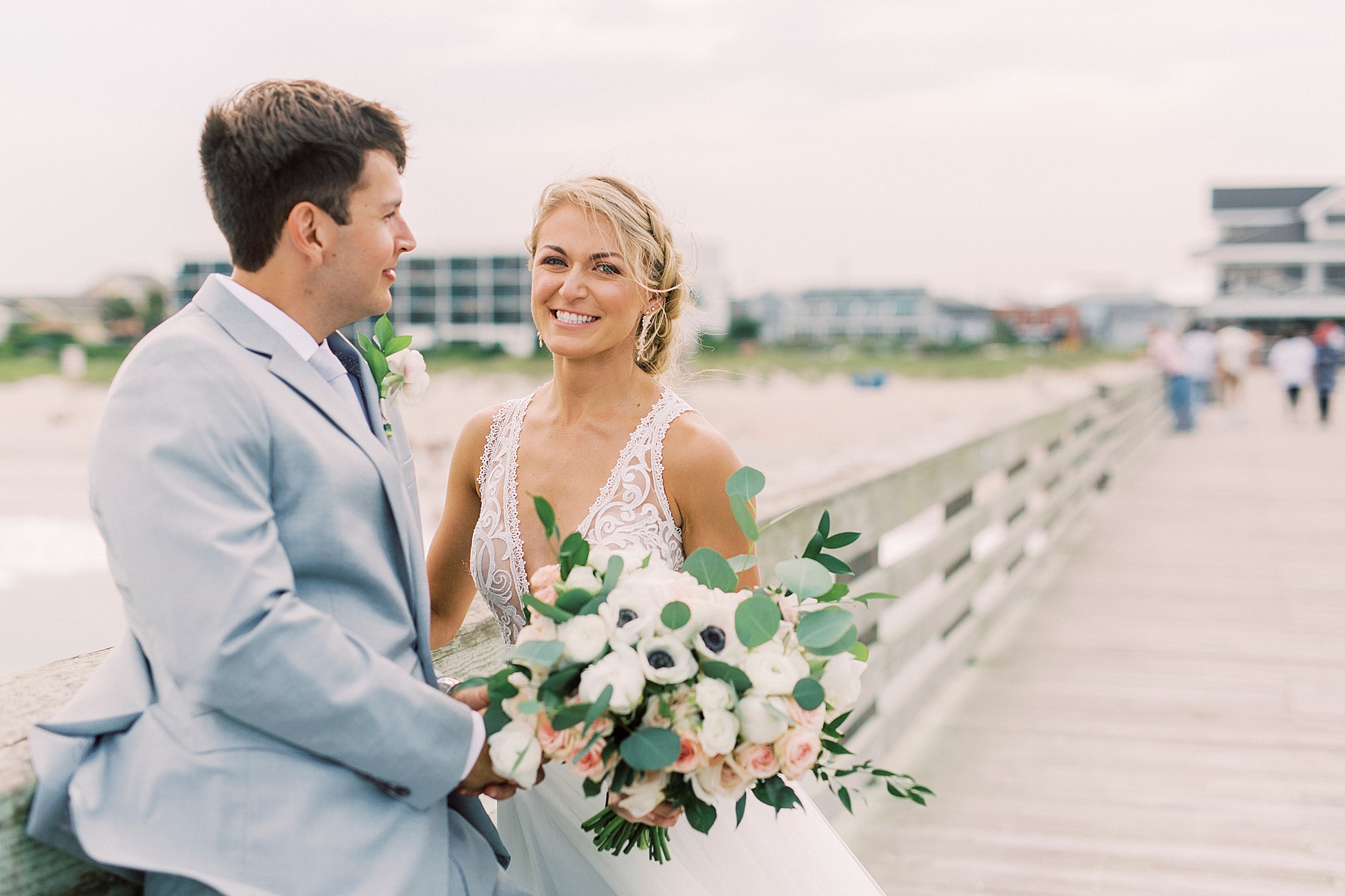 groom smiles at bride during portraits on pier