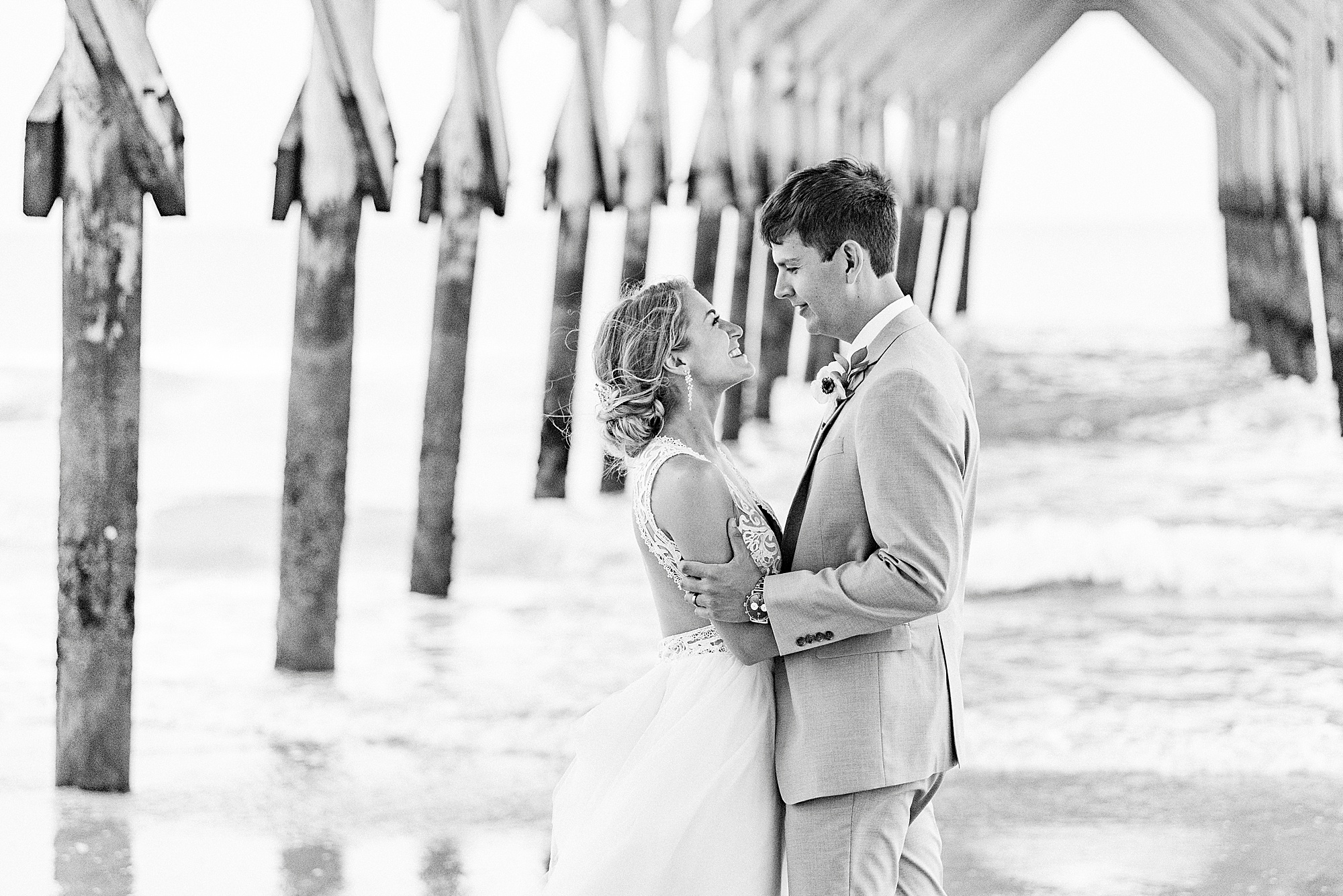 bride and groom pose under pier at Oceanic Restaurant
