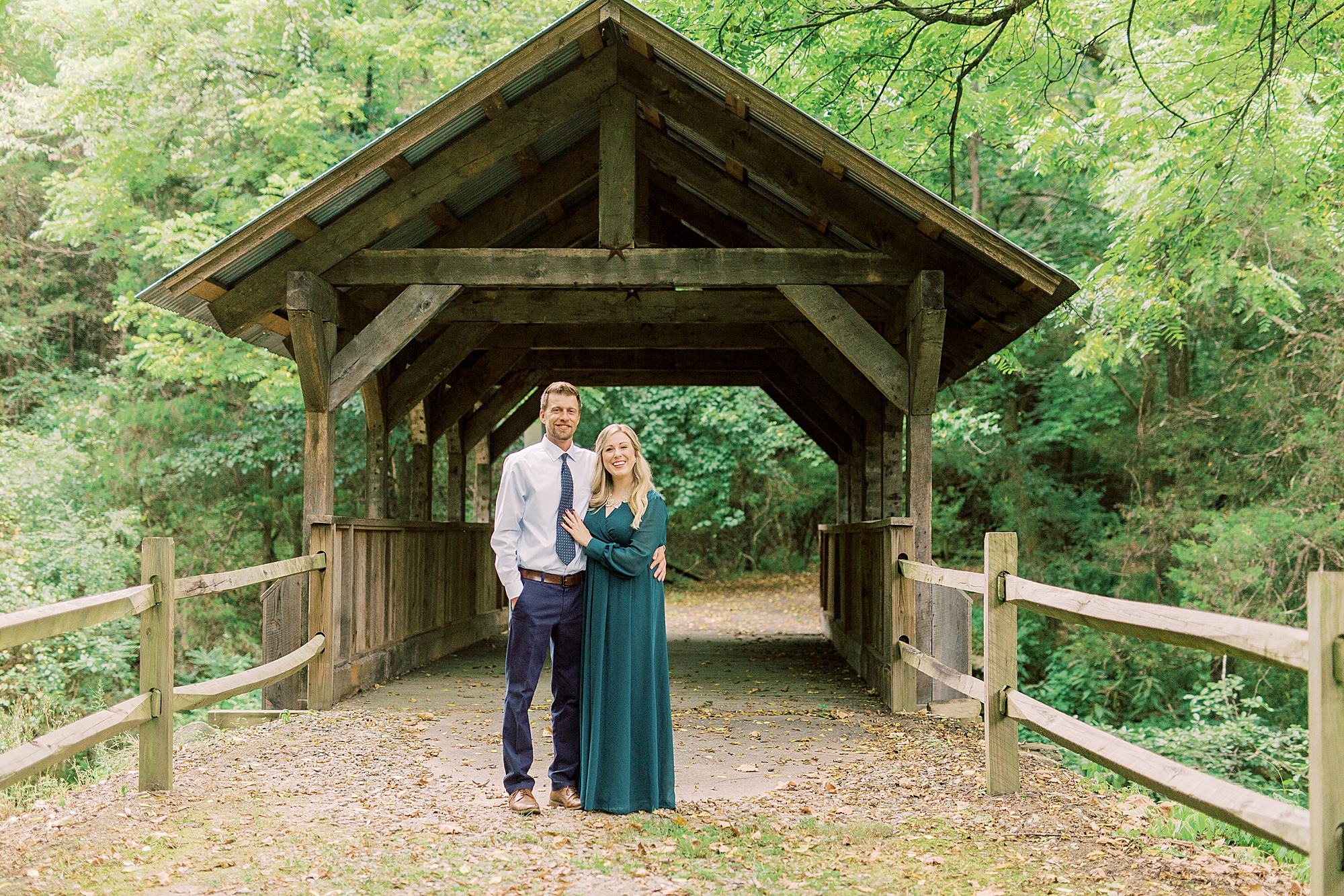 engaged couple stands by covered bridge in Iron Station NC