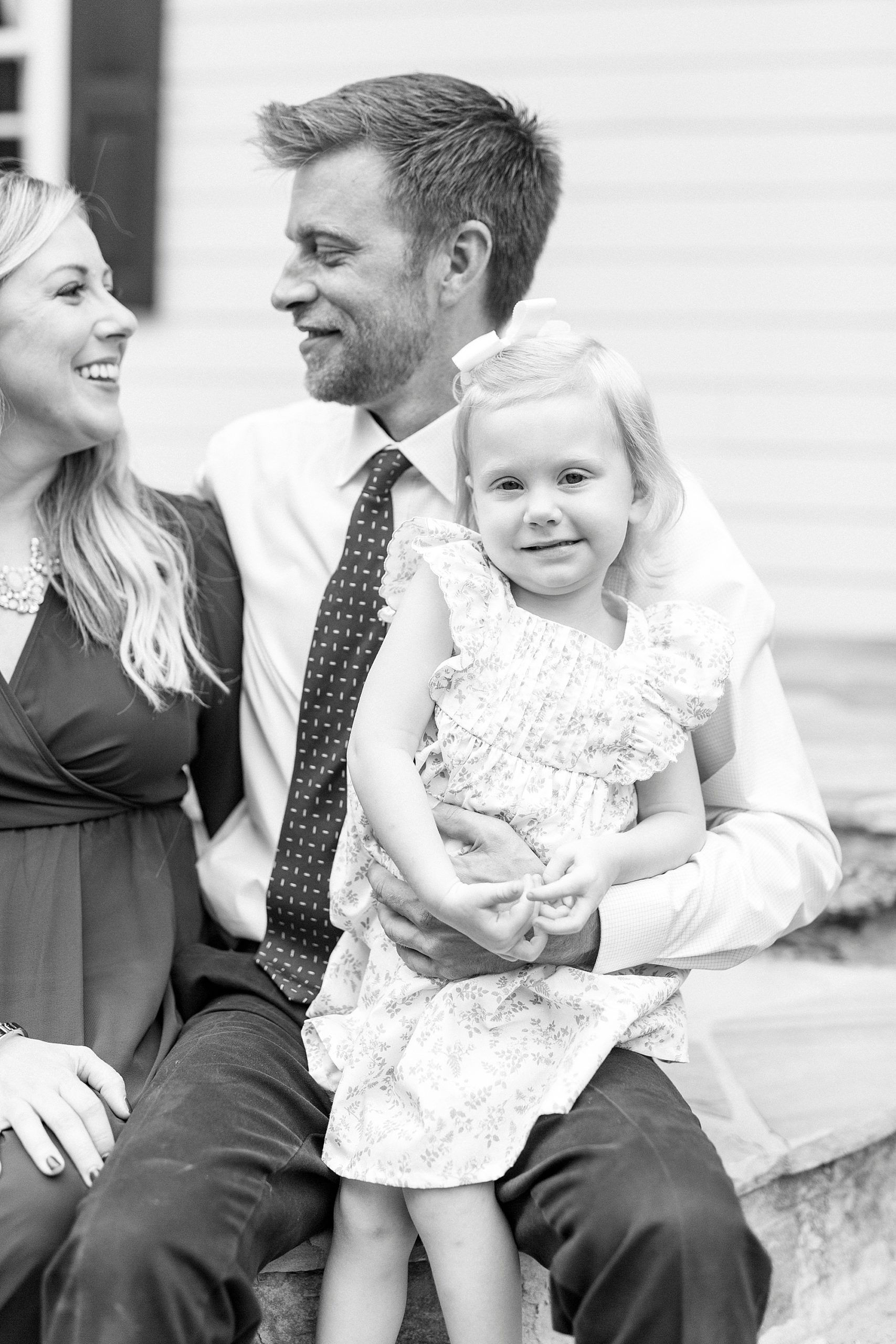 couple looks at each other while holding daughter