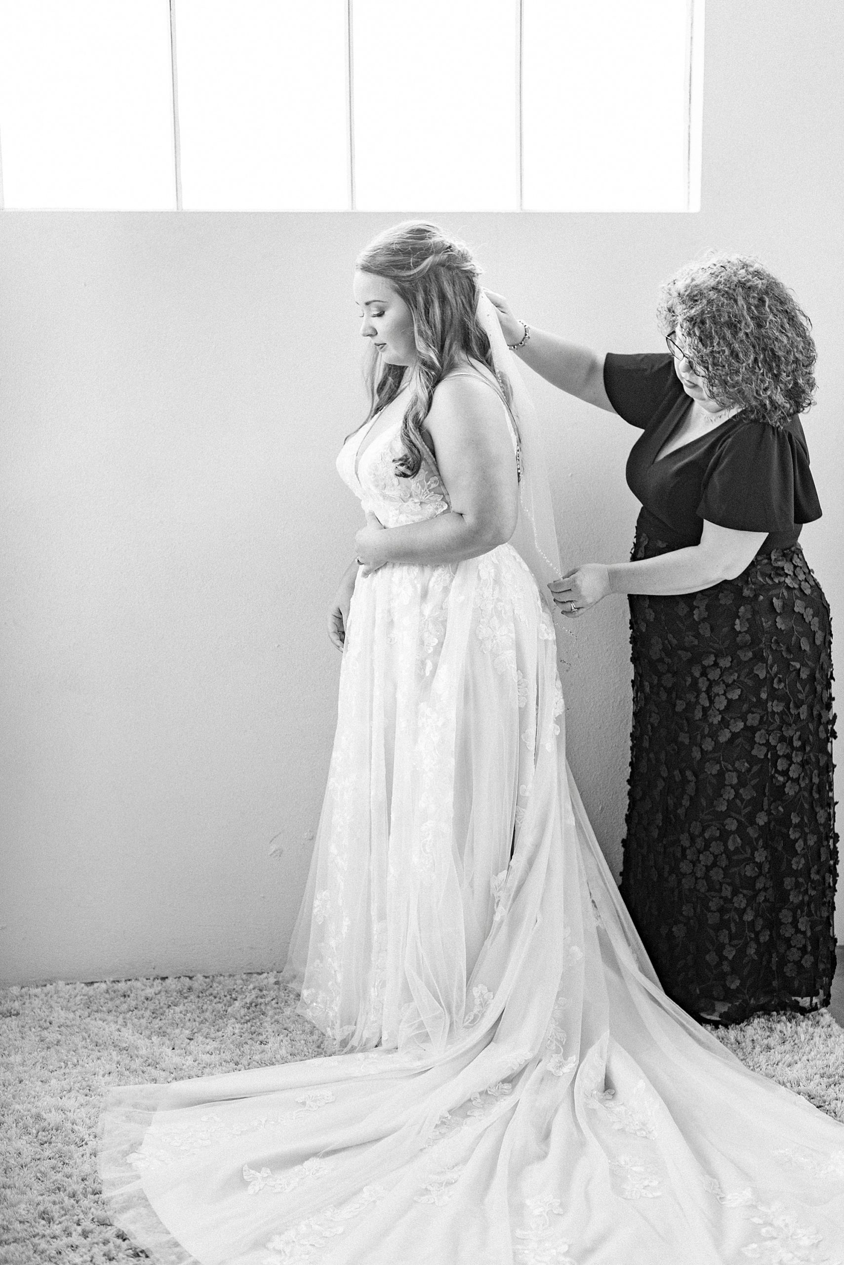 mother helps bride with veil during wedding prep