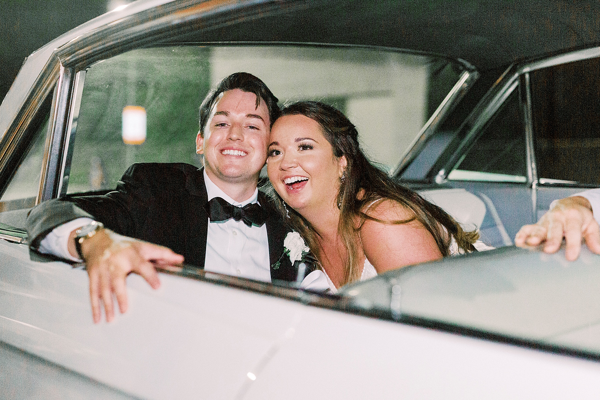 newlyweds laugh in back of car