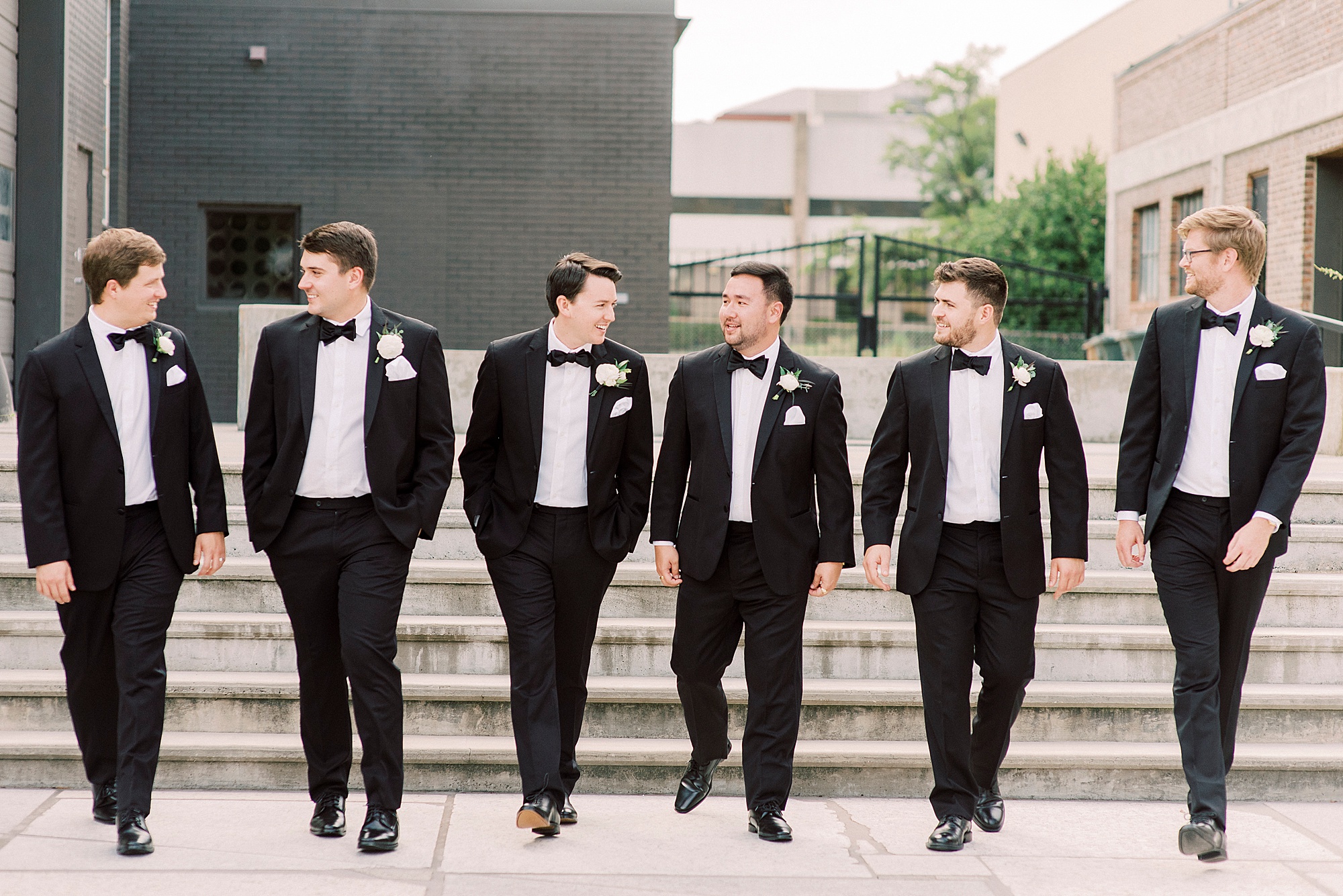 groom walks with groomsmen outside the Cadillac Service Garage