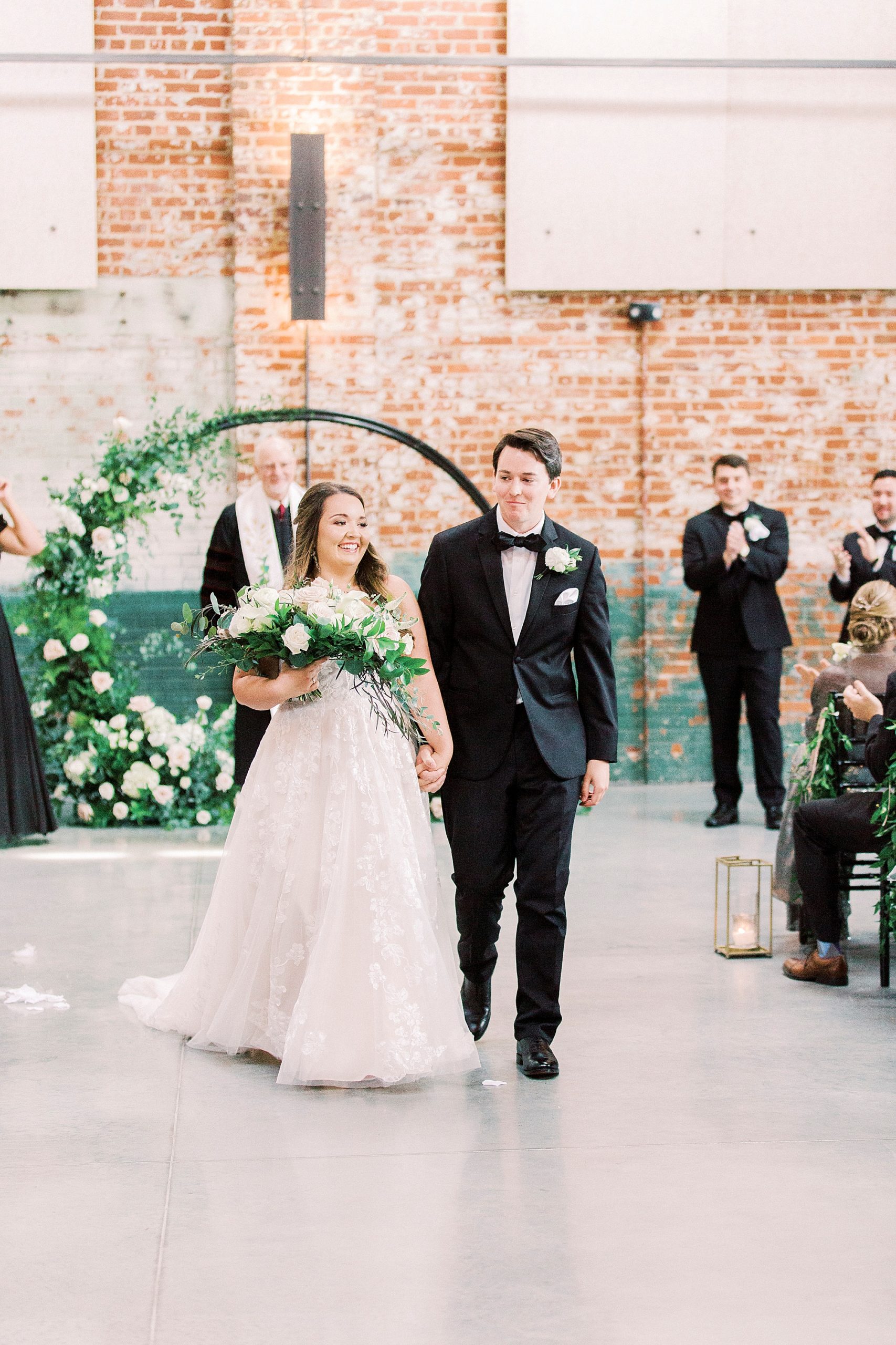 newlyweds walk down aisle after ceremony at the Cadillac Service Garage