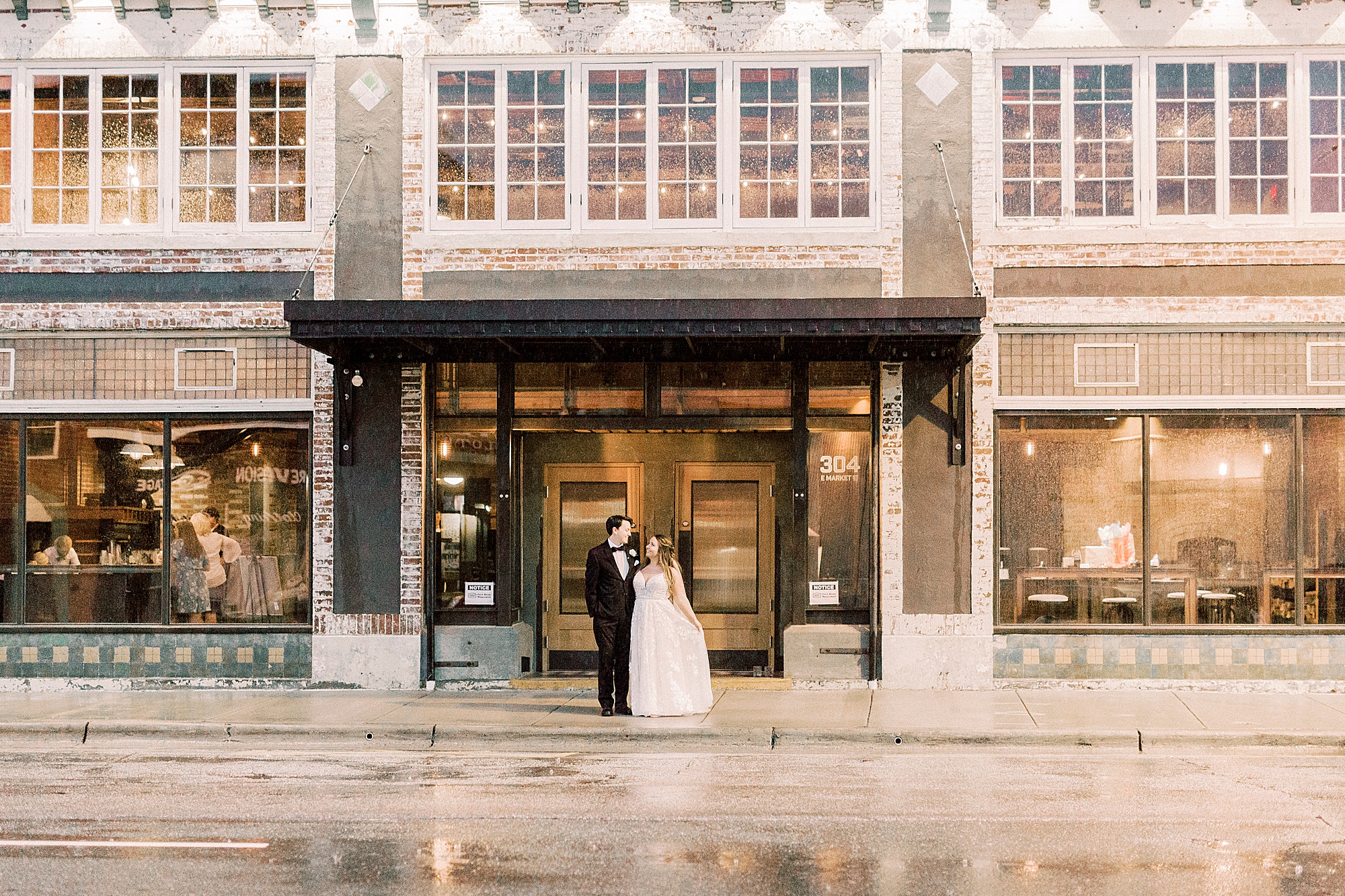 bride and groom kiss outside the doorway of Cadillac Service Garage
