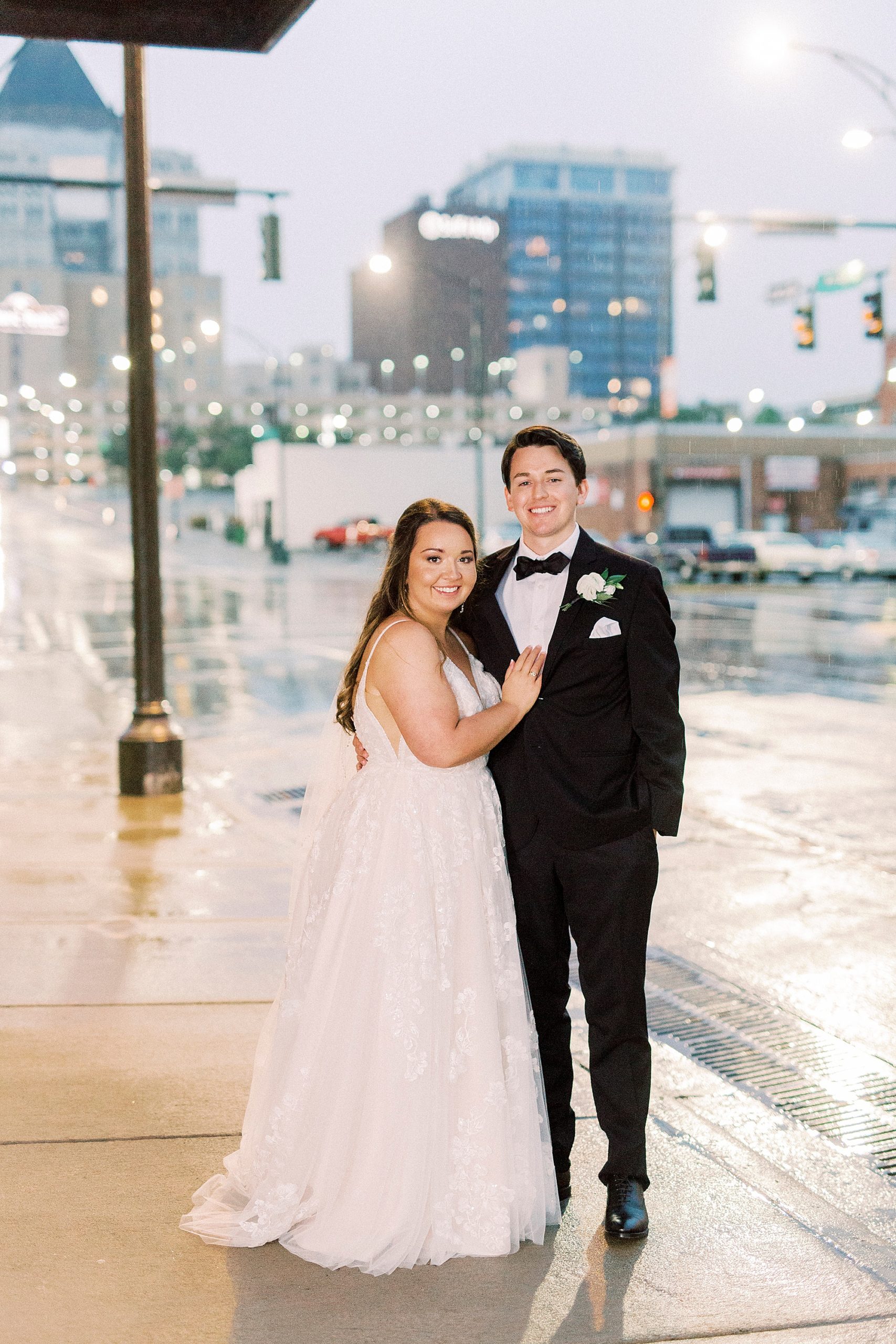 newlyweds pose on rainy street in Greensboro NC