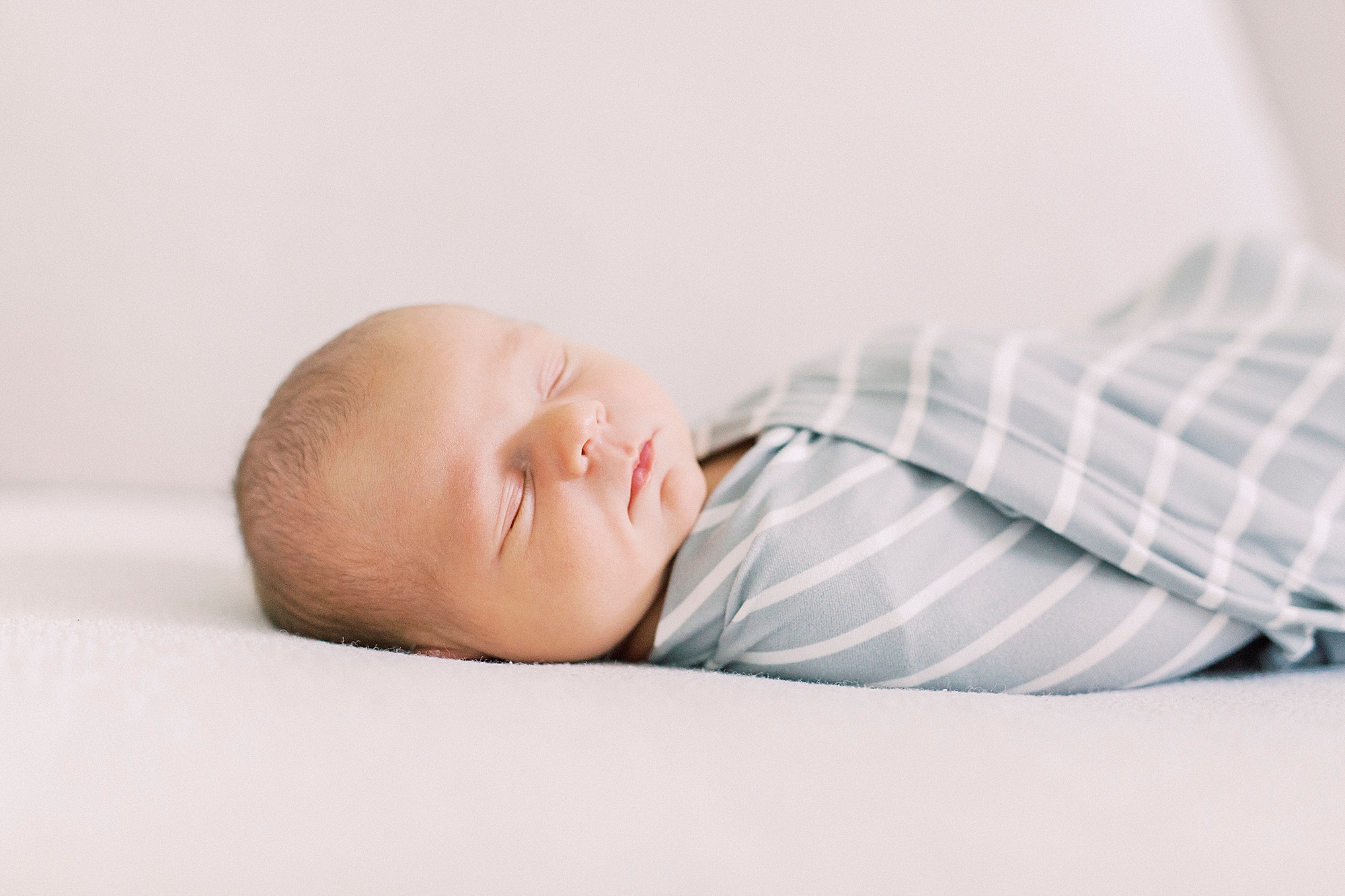 baby in blue and white swaddle sleeps during lifestyle newborn session