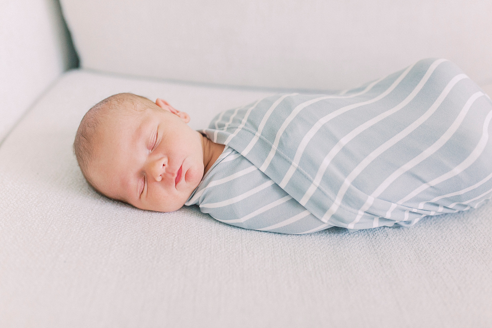 baby sleeps in swaddle on couch during lifestyle newborn session
