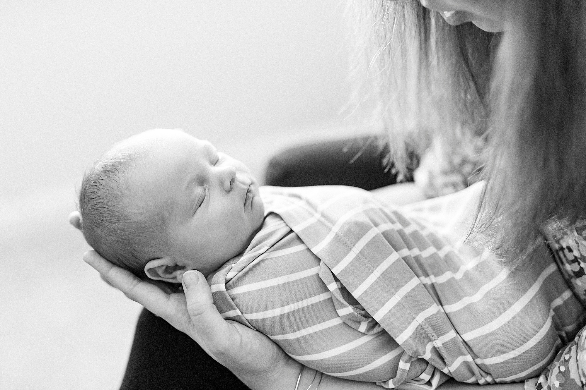baby sleeps in mom's hands during lifestyle newborn session