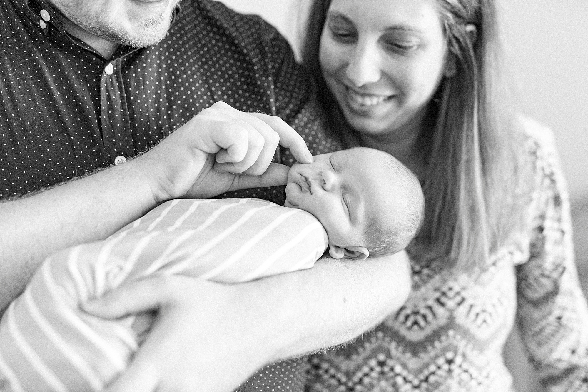 parents touch baby's cheeks during newborn photos