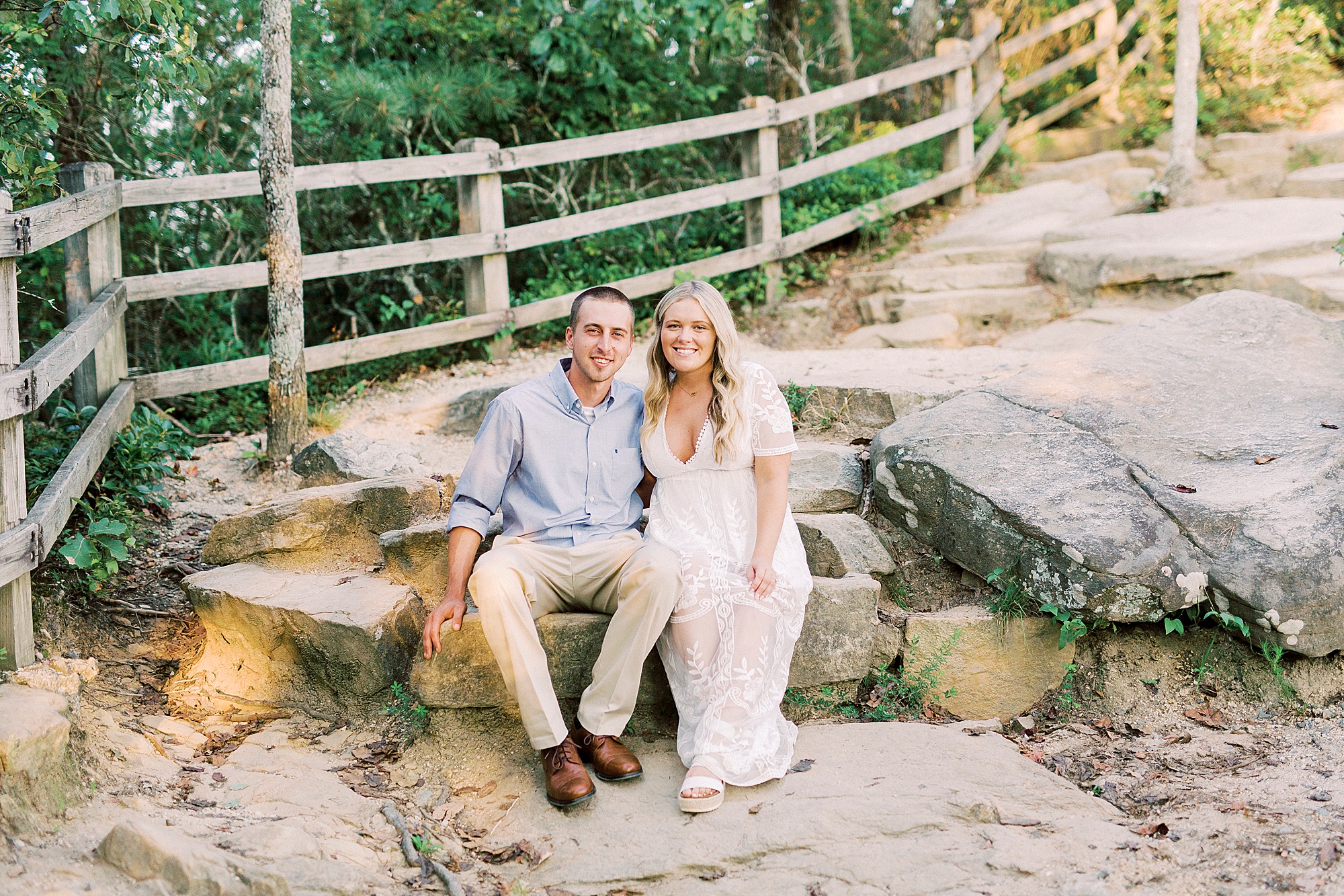 bride and groom sit on rocks during Mount Airy engagement session