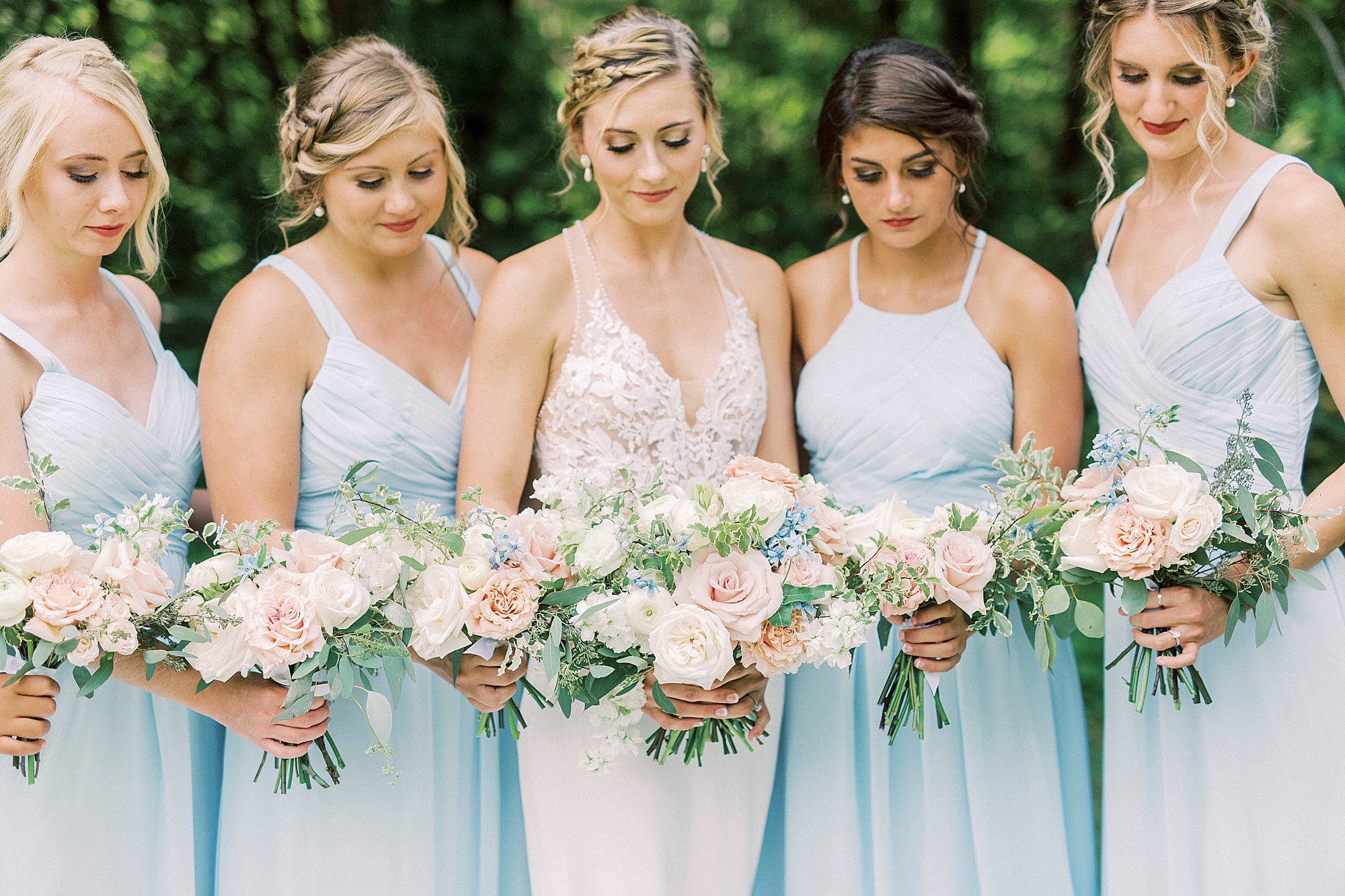 bride and bridesmaids look down at bouquets before Winston Salem wedding