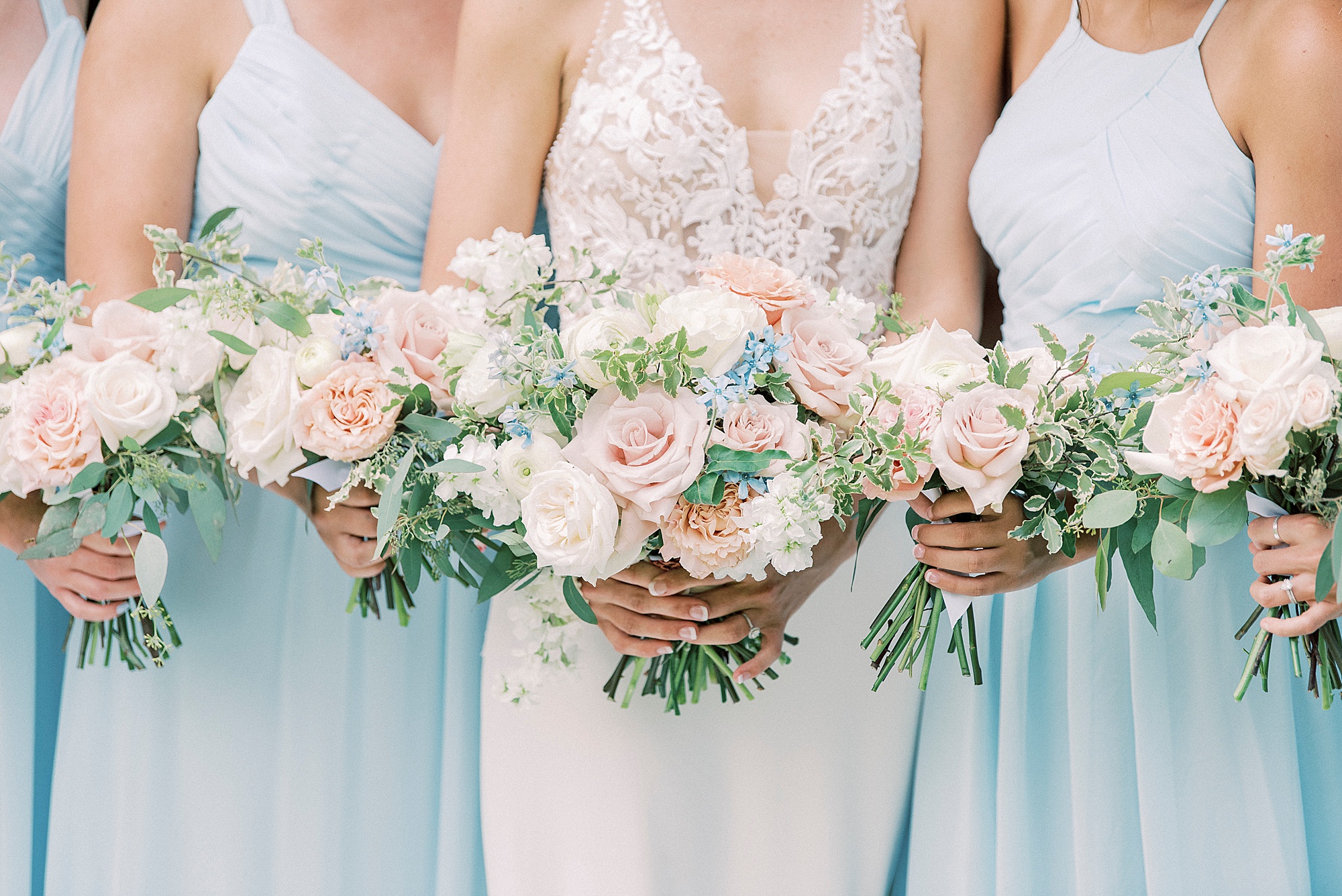 bride and bridesmaids hold bouquets of pastel flowers