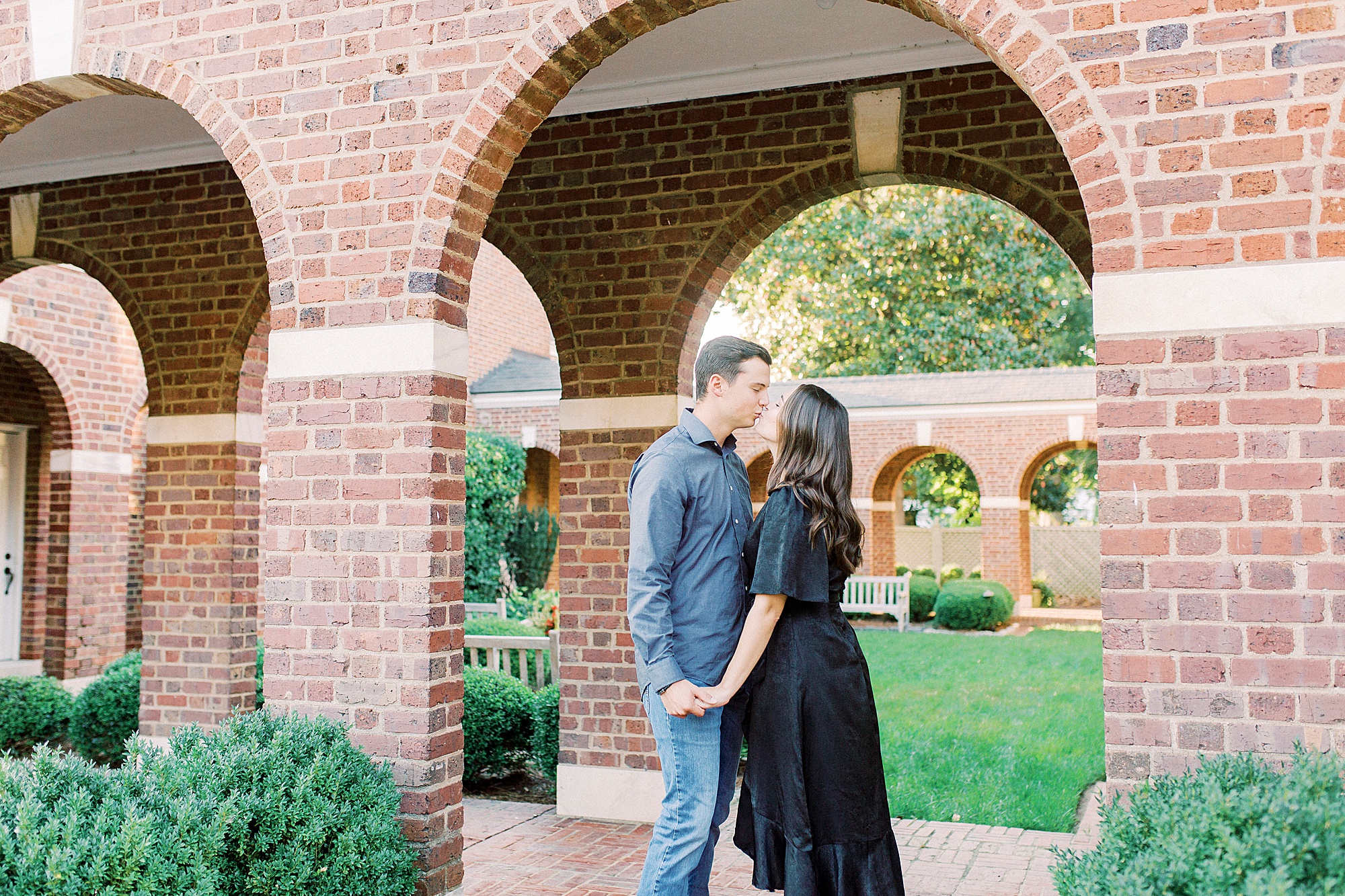 bride and groom kiss under brick arch in Downtown Concord