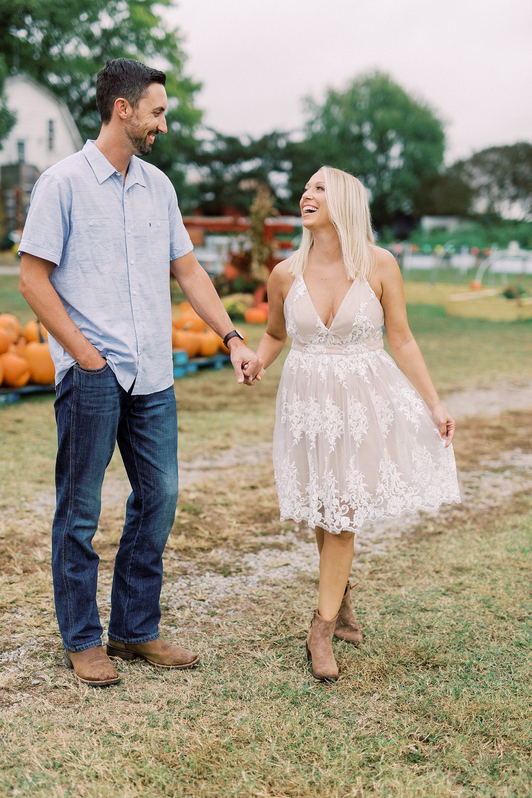 bride and groom hold hands walking through pumpkin patch