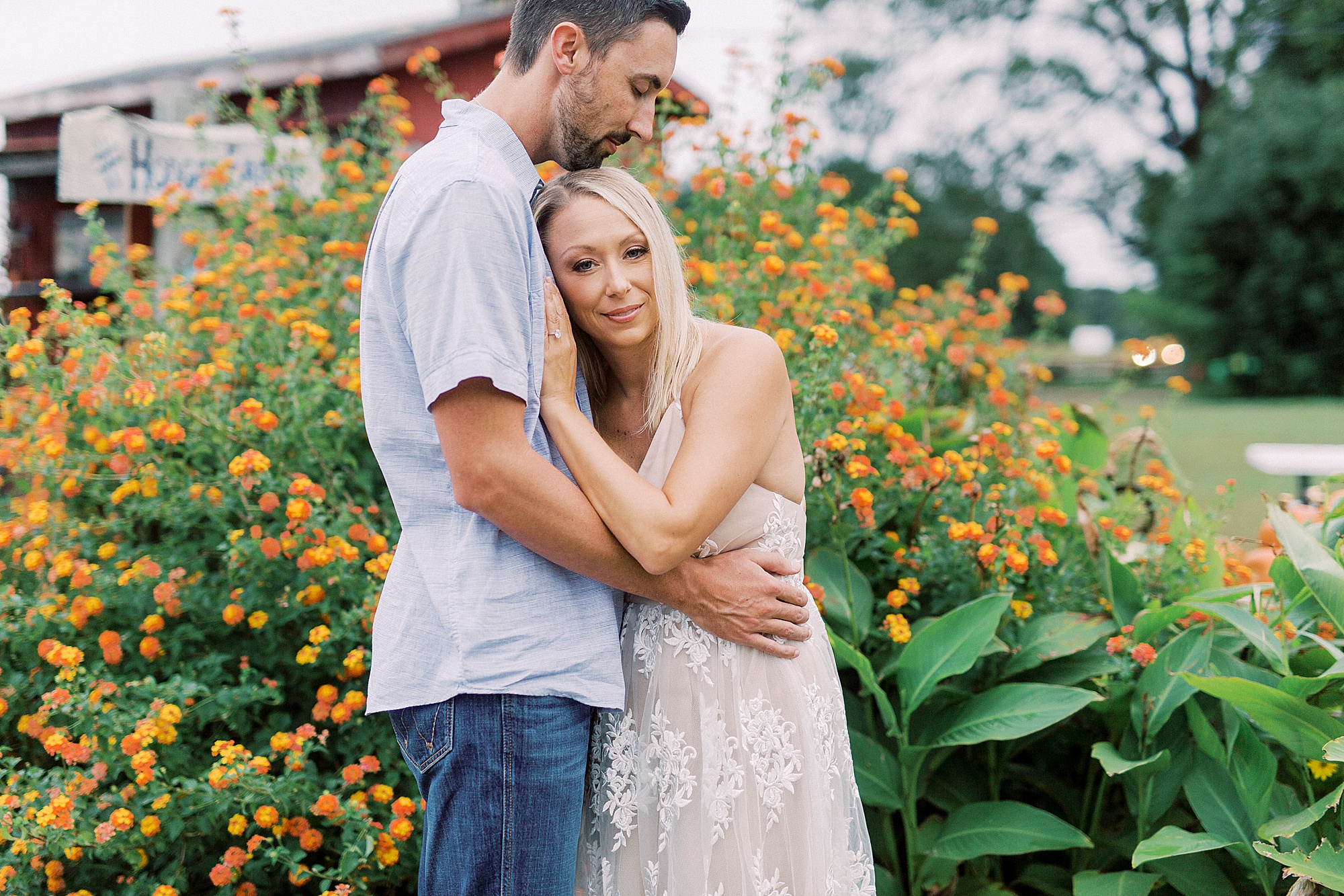 engaged couple hugs by orange flowers at Hodges Family Farm