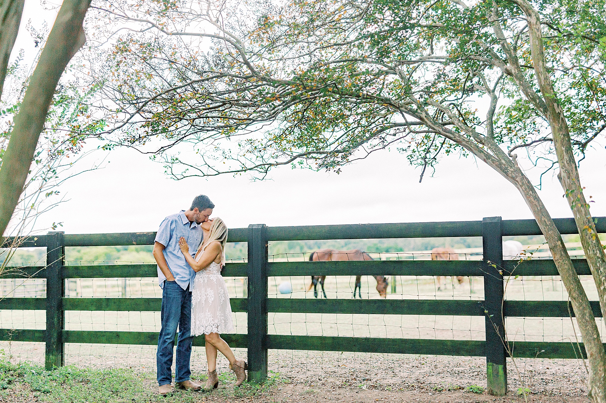 engaged couple poses by fence during NC engagement portraits