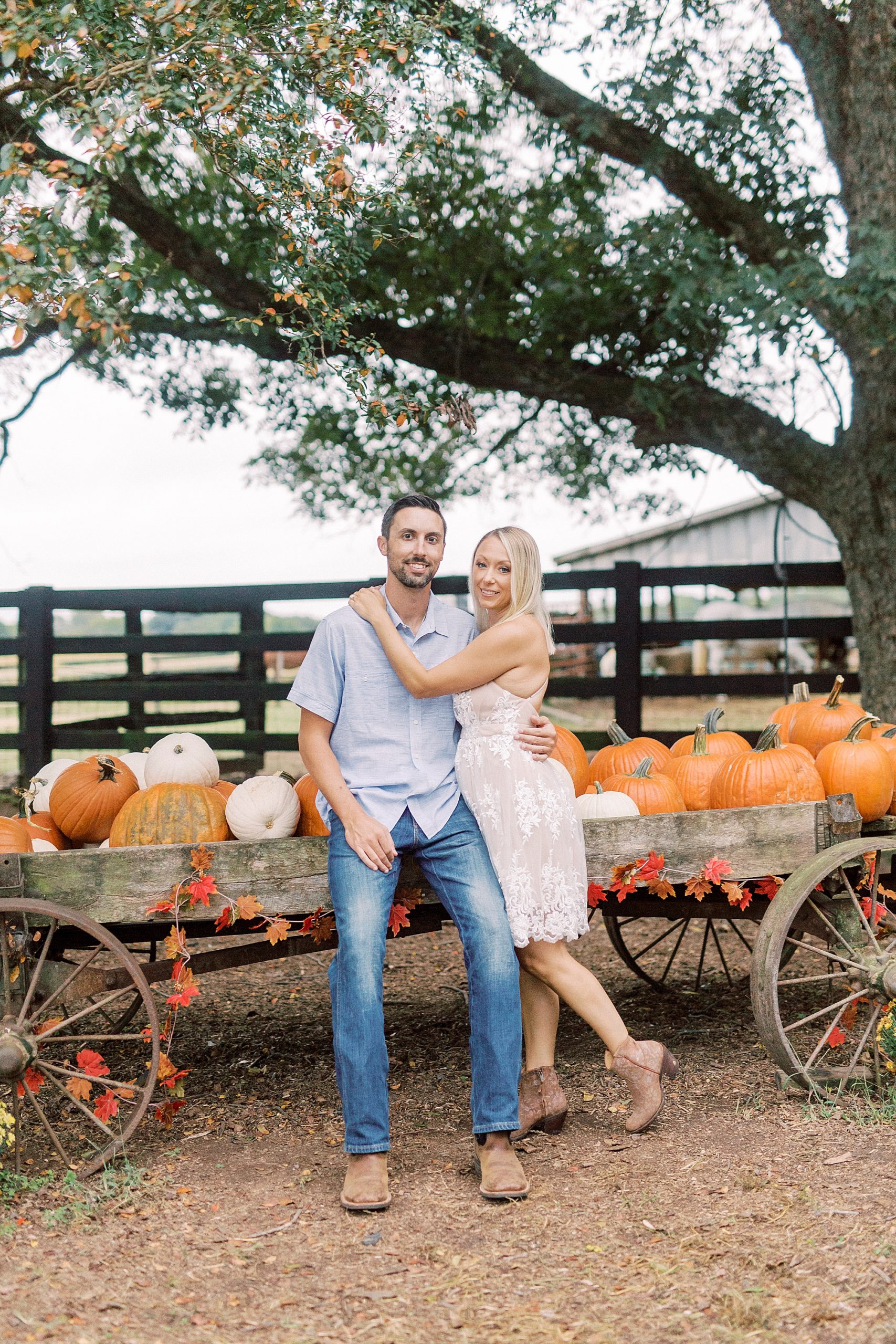 bride and groom lean against wagon with pumpkins at Hodges Family Farm