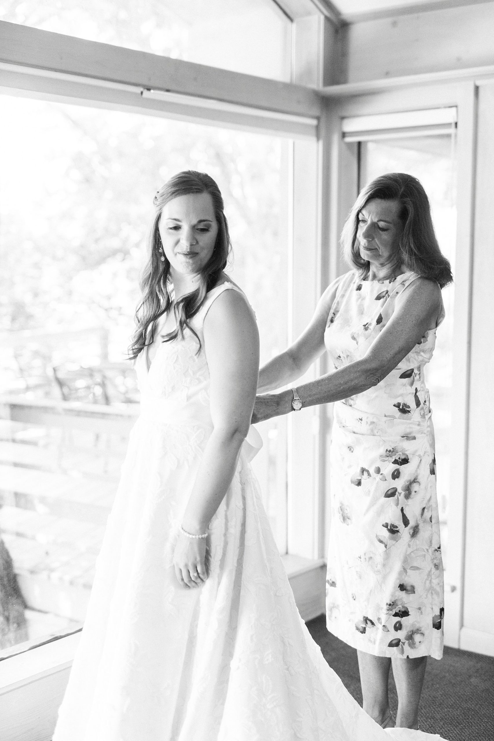 mother helps bride with buttons on wedding dress