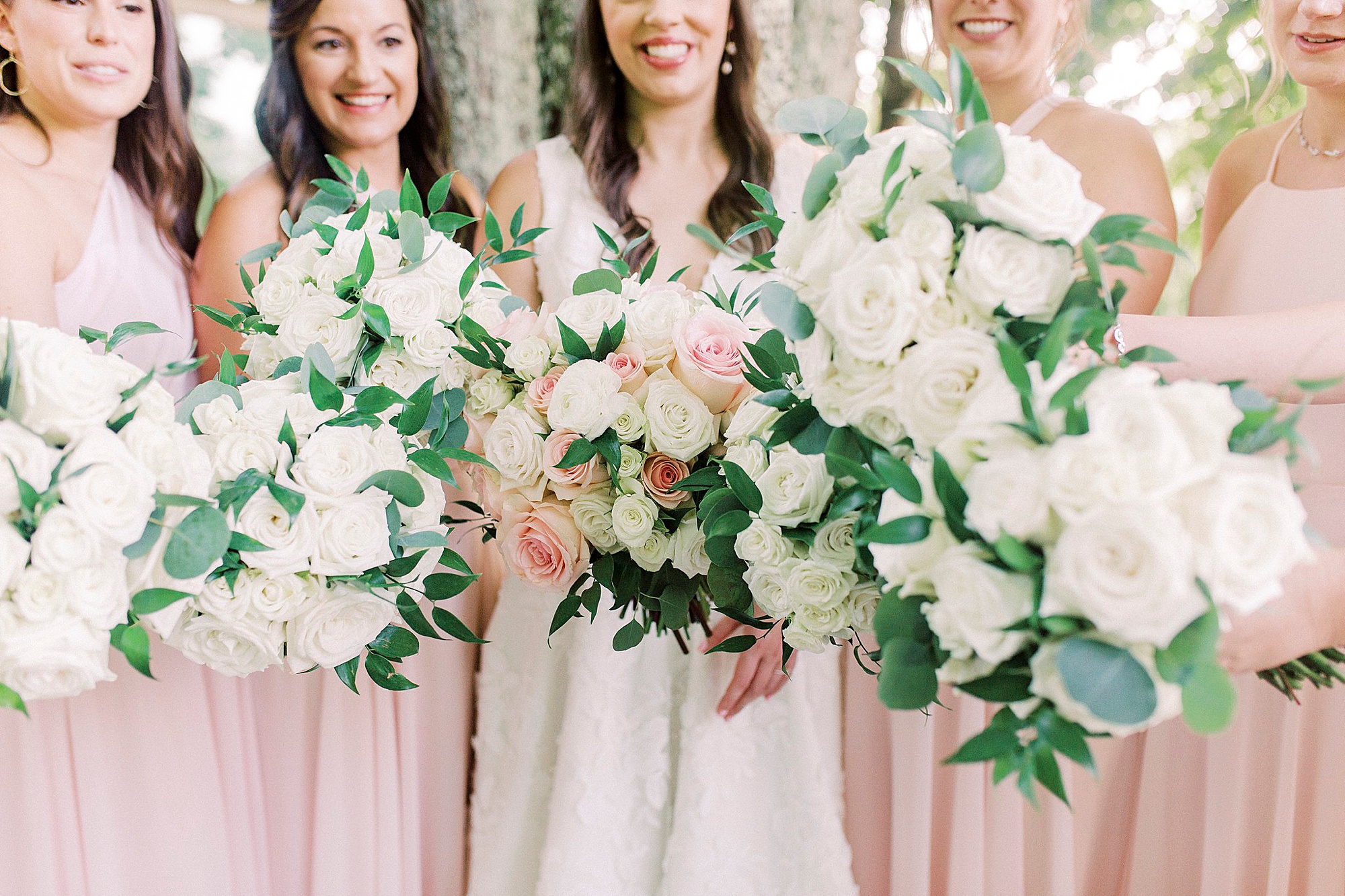 bridesmaids hold bouquets of white and pink flowers
