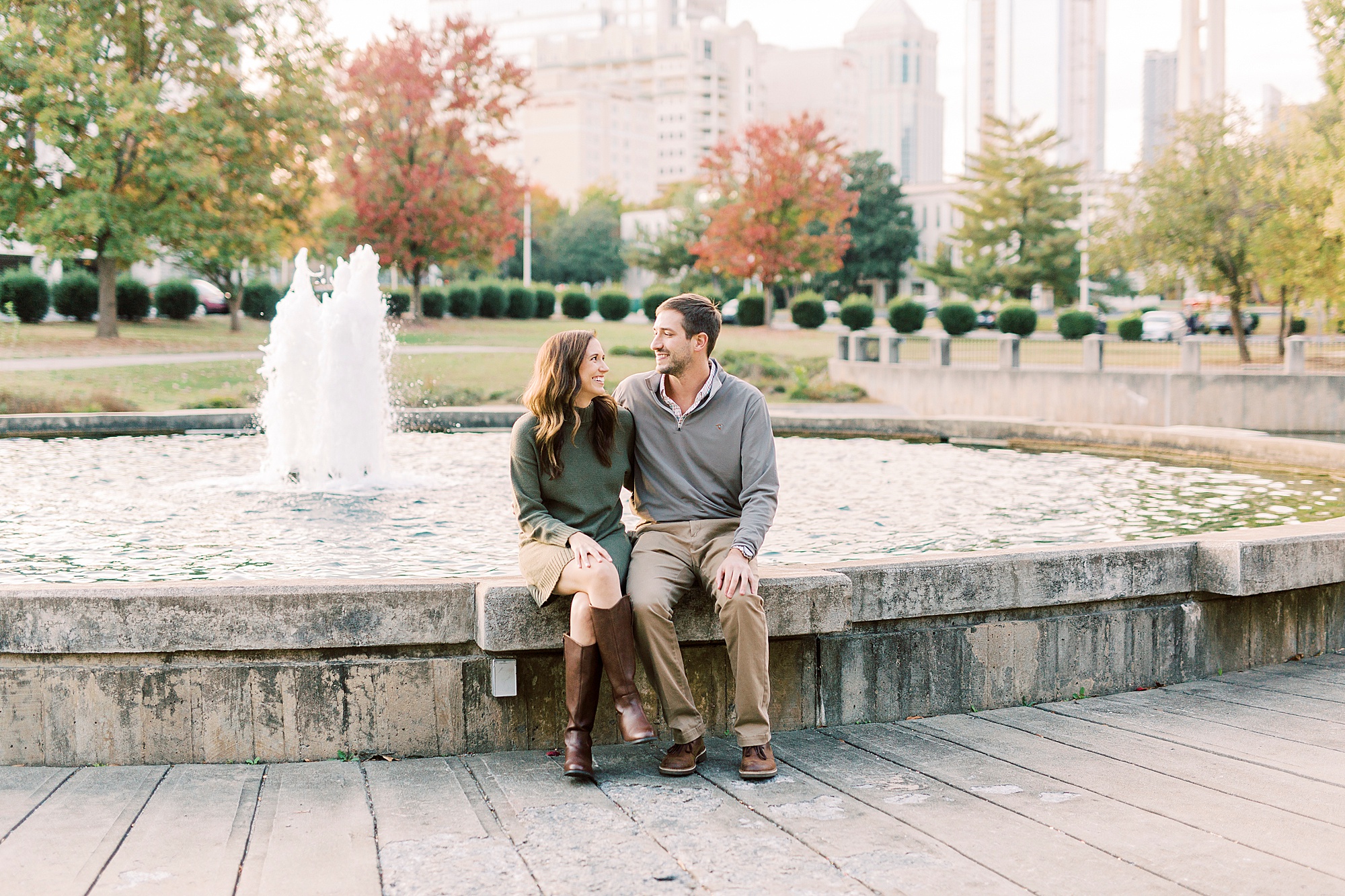 couple sits on fountain during Marshall Park engagement session