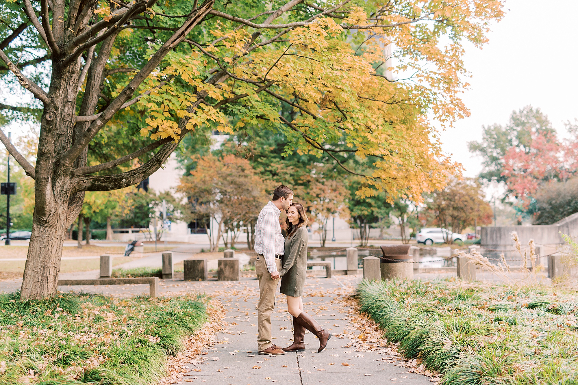 groom holds bride's hands and kisses her forehead during Marshall Park engagement session