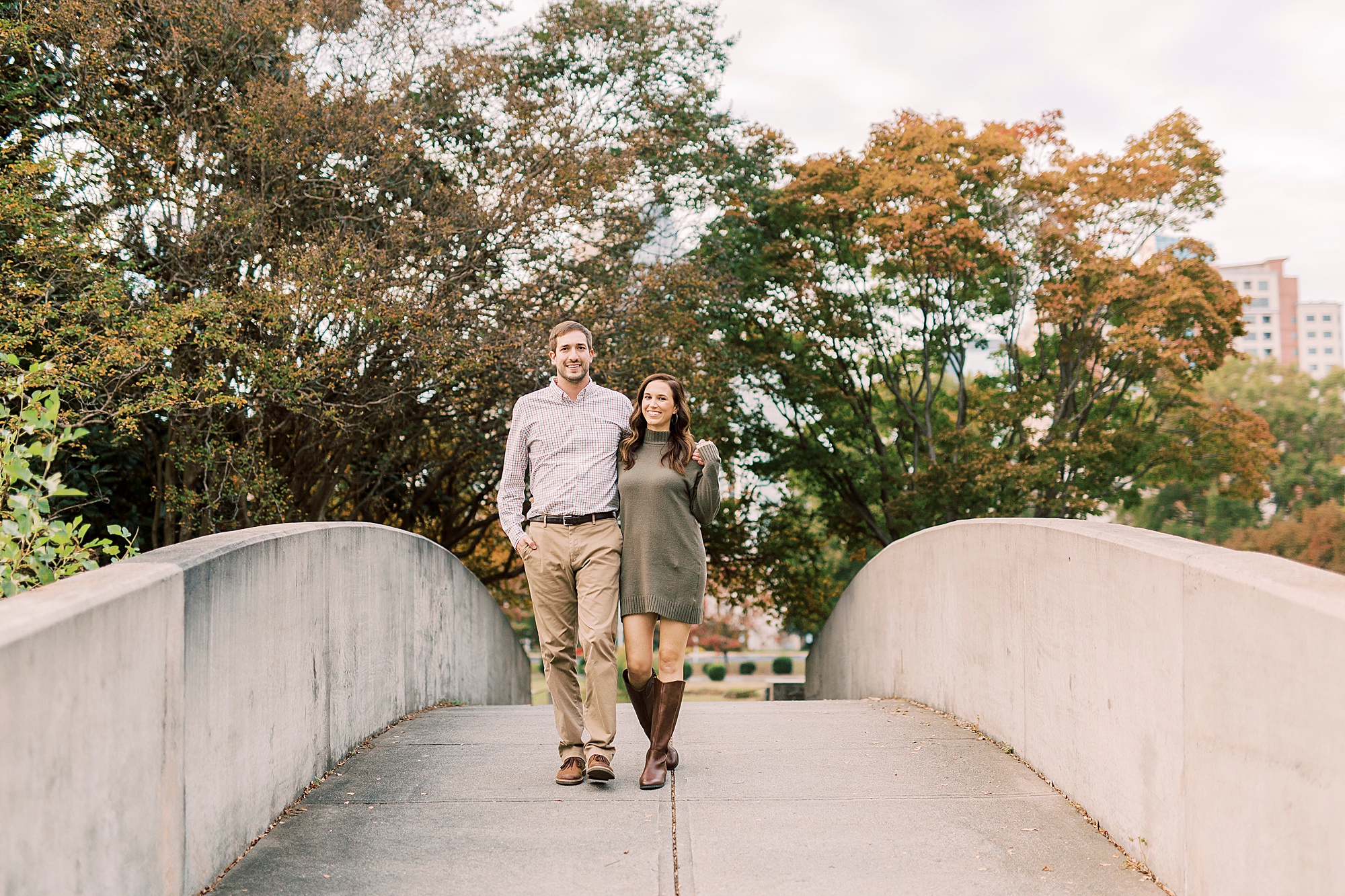 couple walks over bridge during Marshall Park engagement session