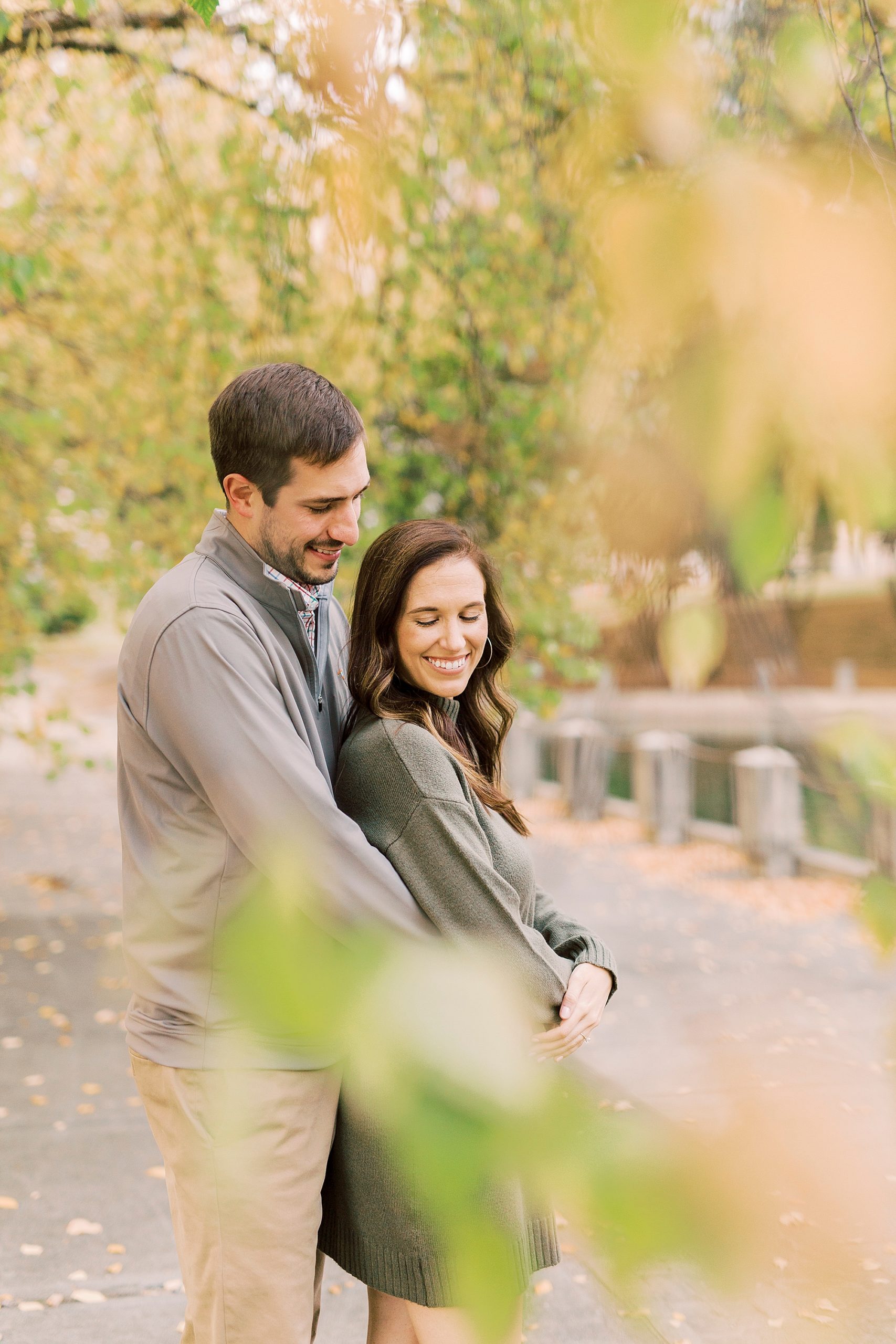 man hugs woman from behind during fall engagement session