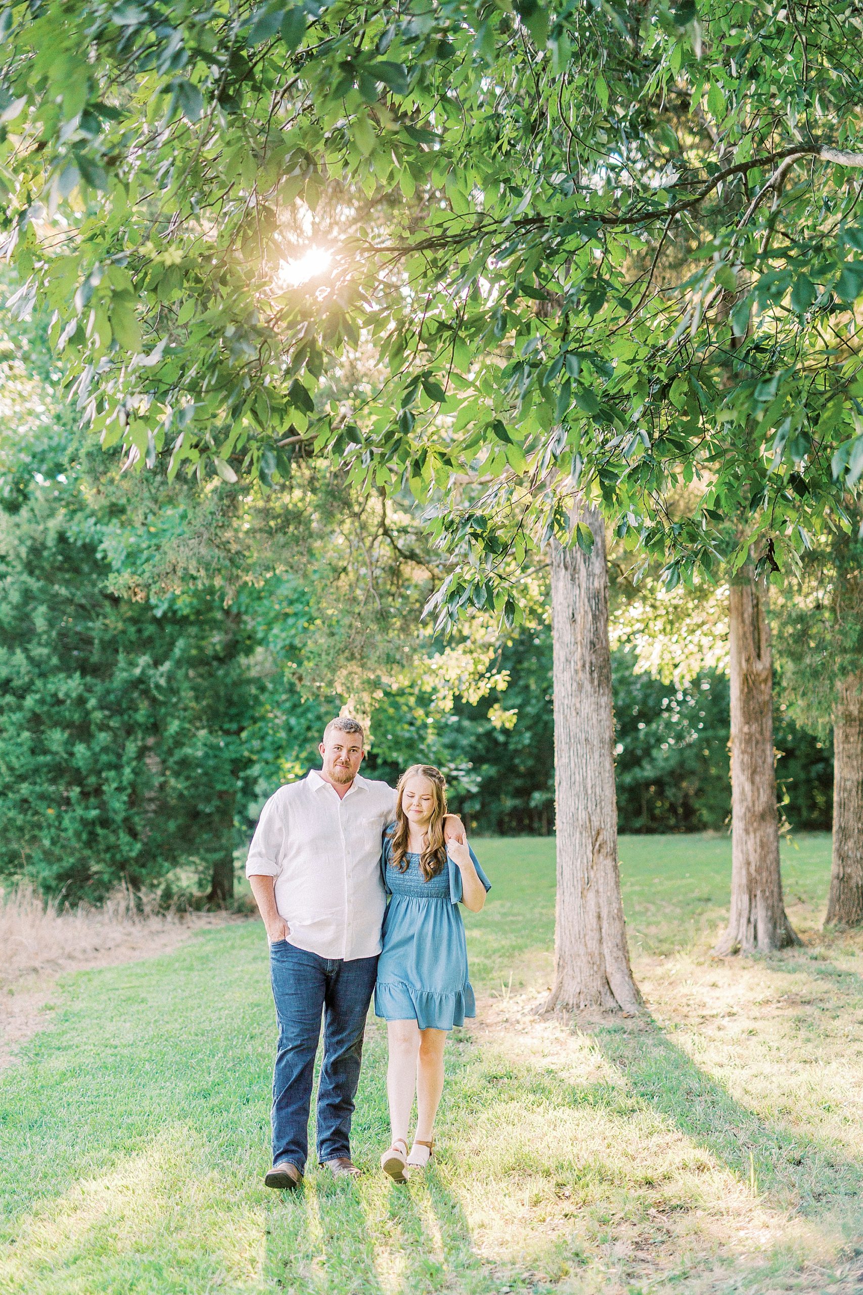 couple walks through grove of trees during Sunset Farm engagement session