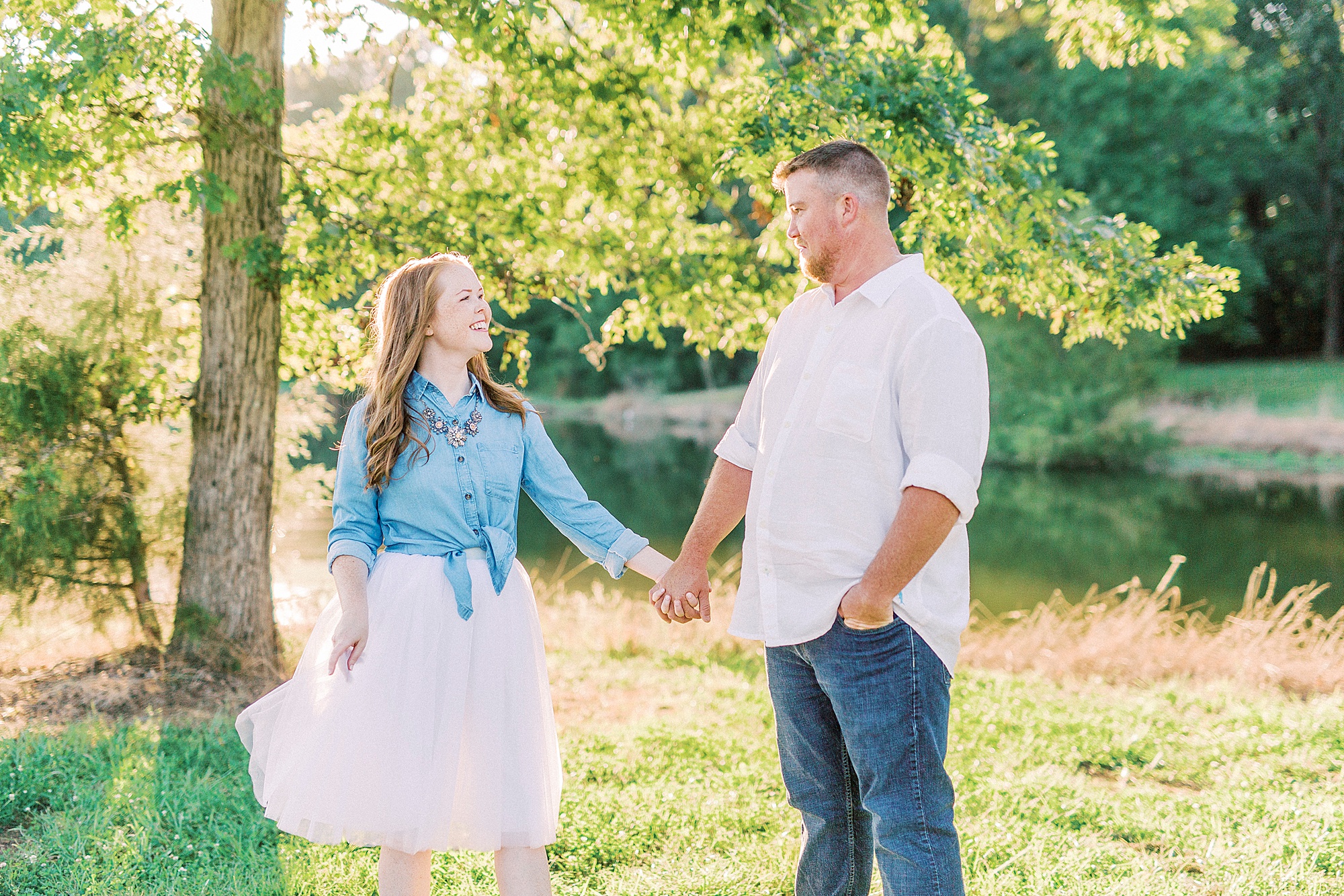 bride and groom hold hands looking at each other during Sunset Farm engagement session