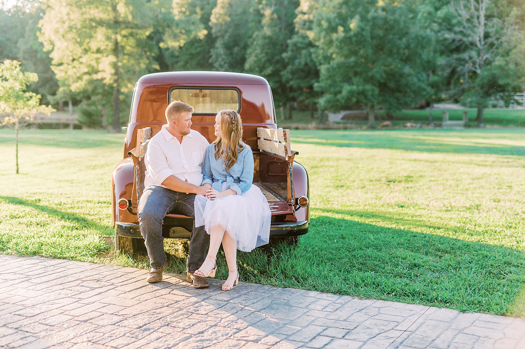 bride and groom sit on truck bed during Sunset Farm engagement session