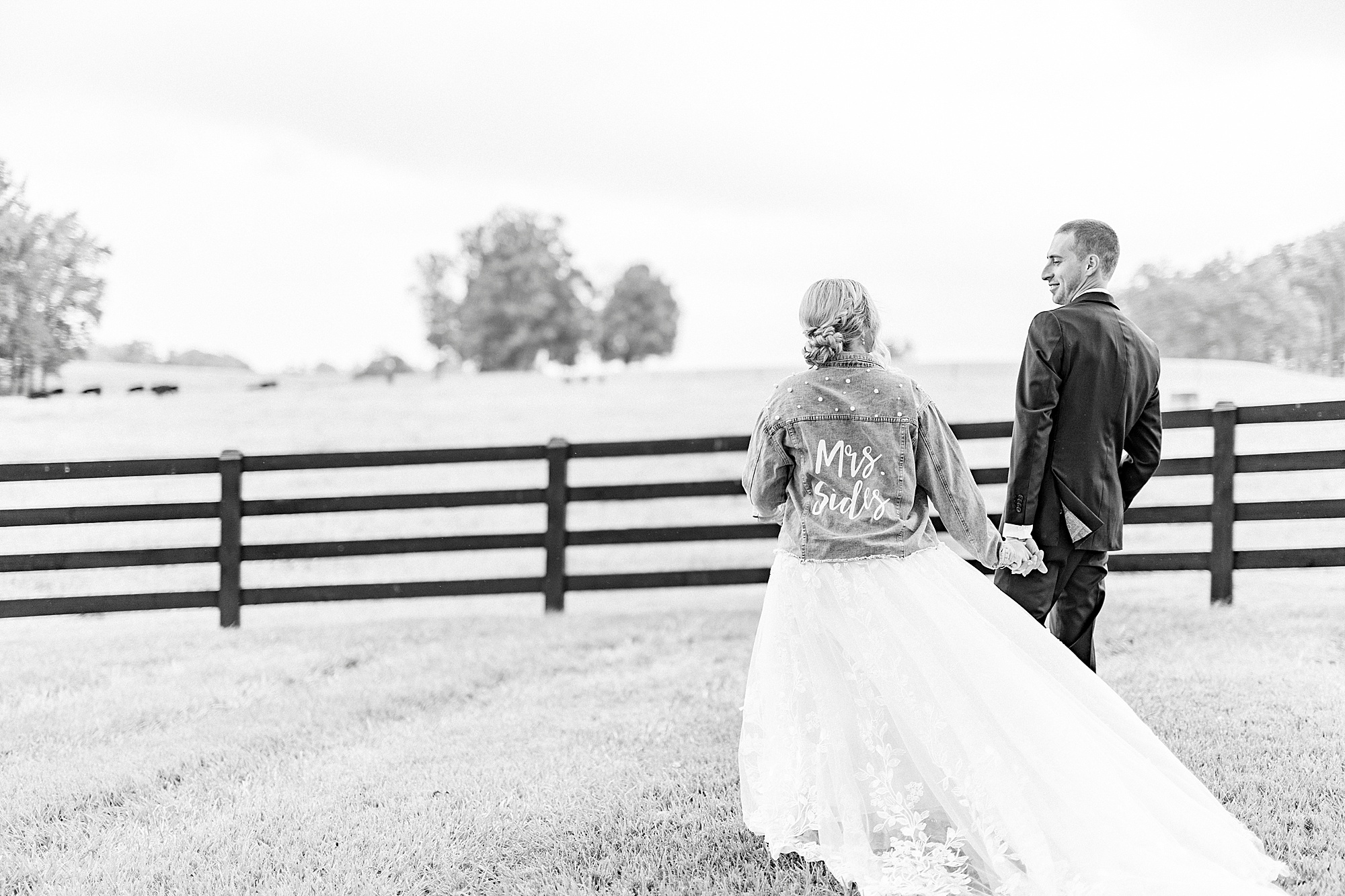 bride walks wearing jean jacket with married name during portraits at Addison Farm