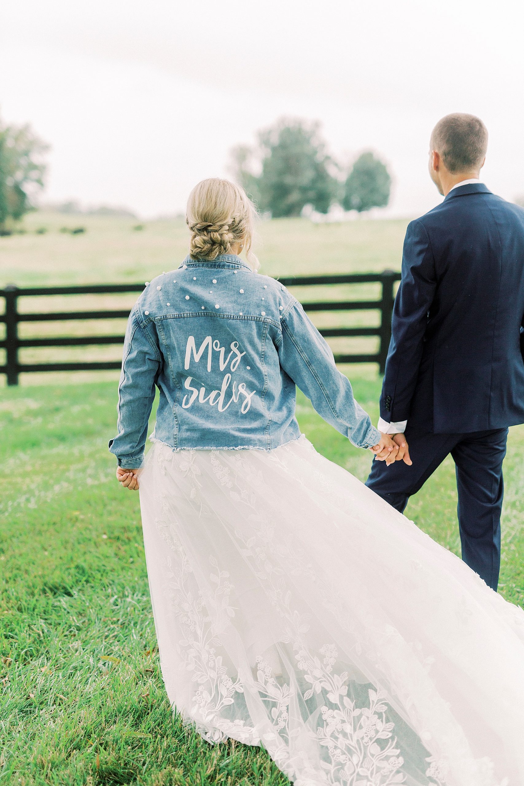 bride walks with jean jacket during Addison Farm wedding portraits