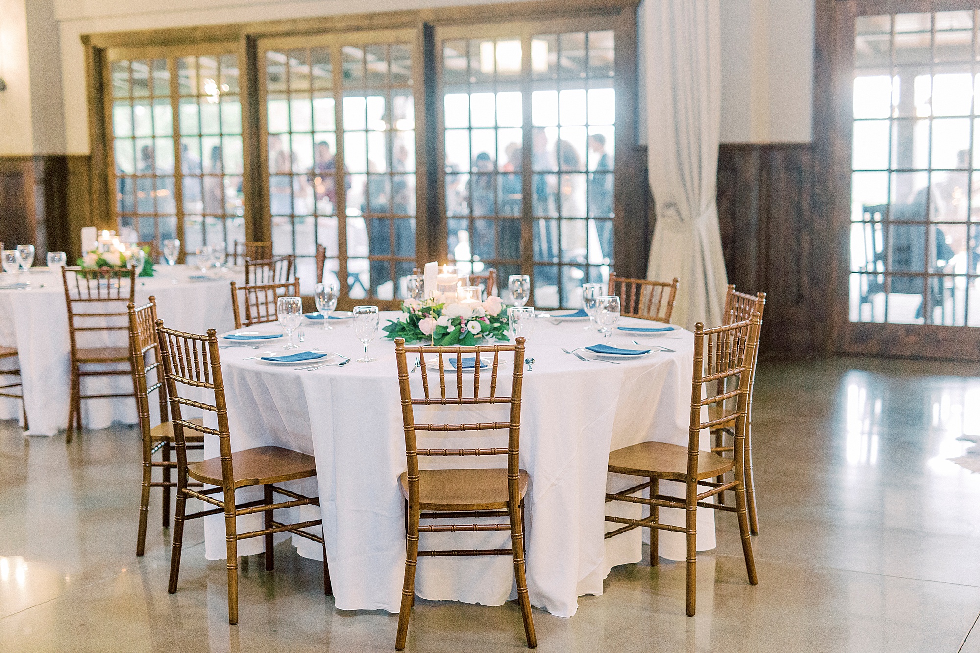 tables with white centerpieces and blue napkins at Greensboro NC wedding reception