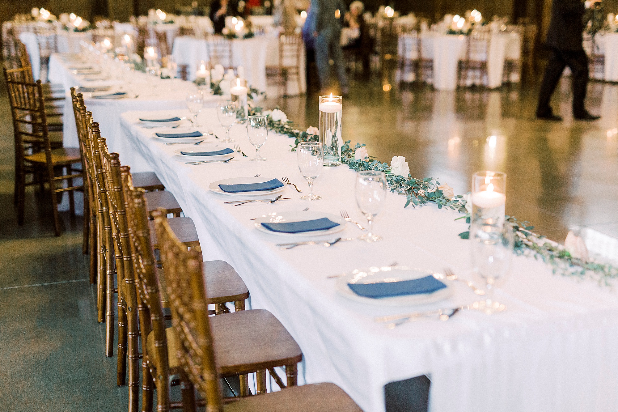 wedding reception table with blue napkins and greenery