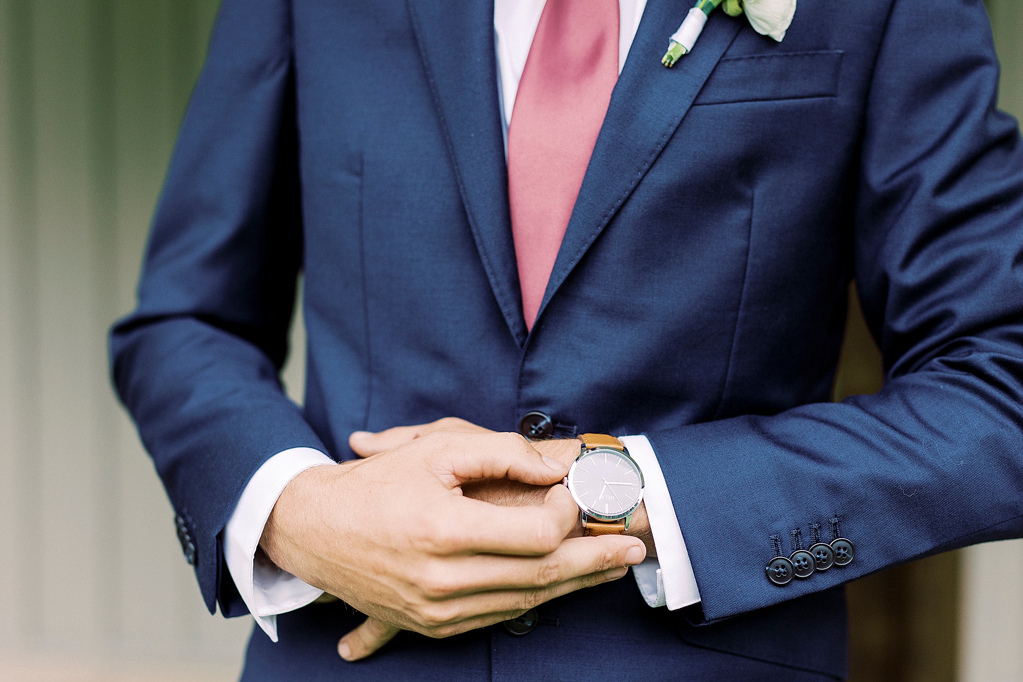 groom adjusts wristwatch during wedding portraits
