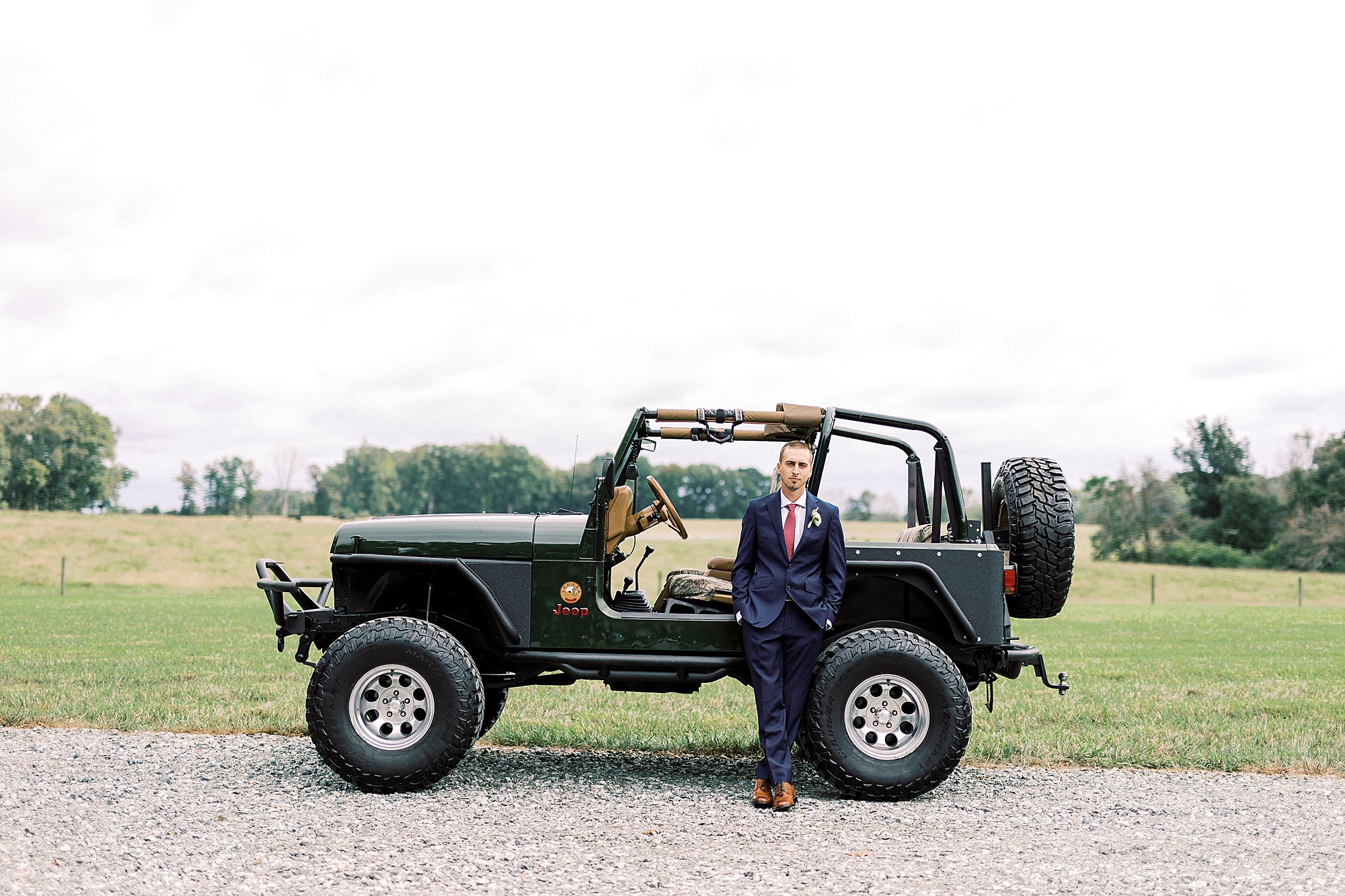 groom poses with Jeep on wedding day at Addison Farm