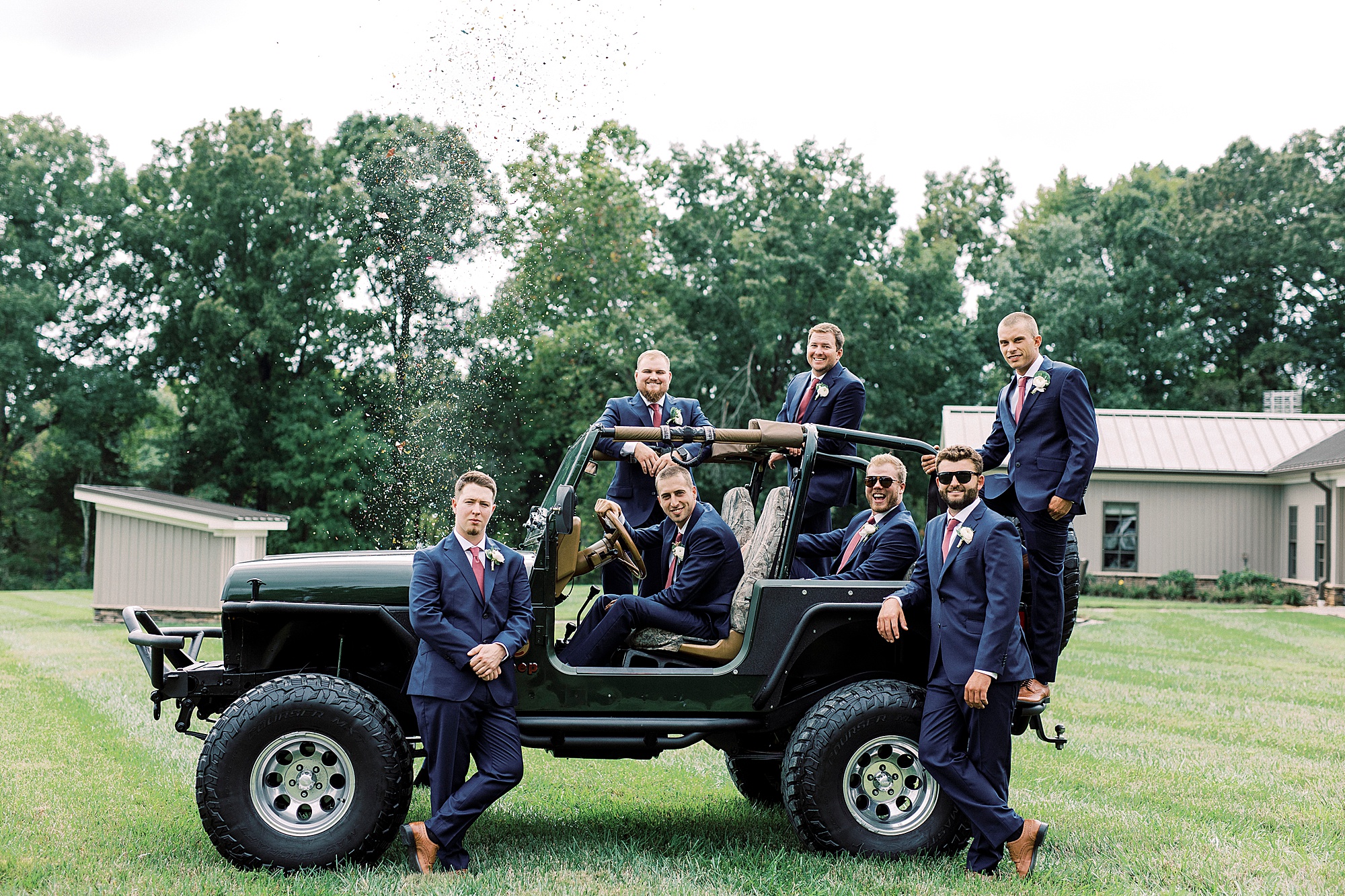 groom stands with groomsmen outside Jeep